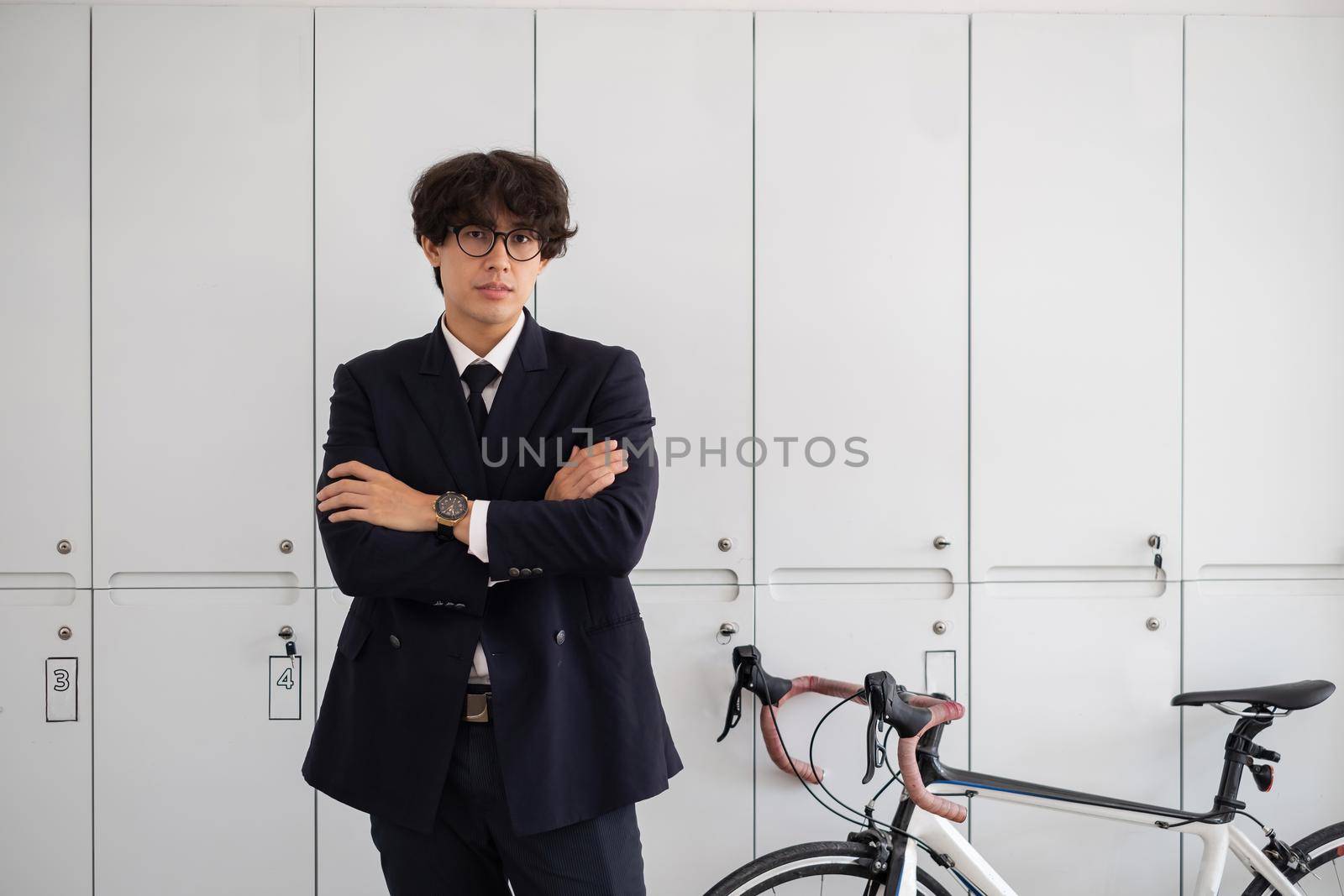 Handsome young asian businessman in suit with bicycle at work place.