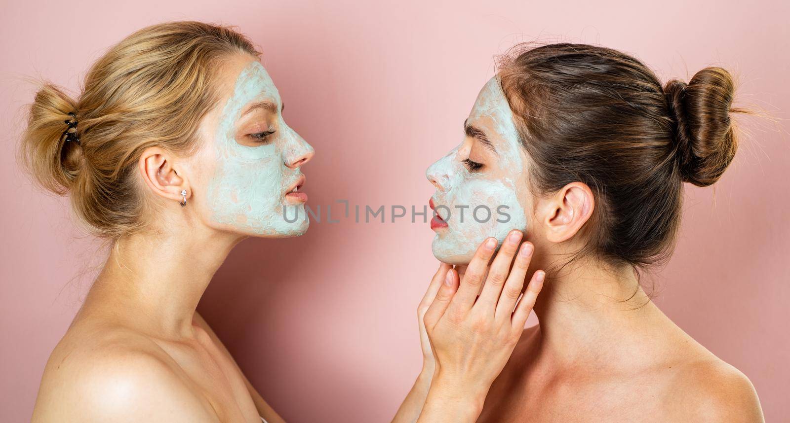 Healthy natural tender girls do beauty spa procedures with clay mud mask at face. Happy funny mood. Healthy and wellness concept. Women with bare shoulders do spa procedures