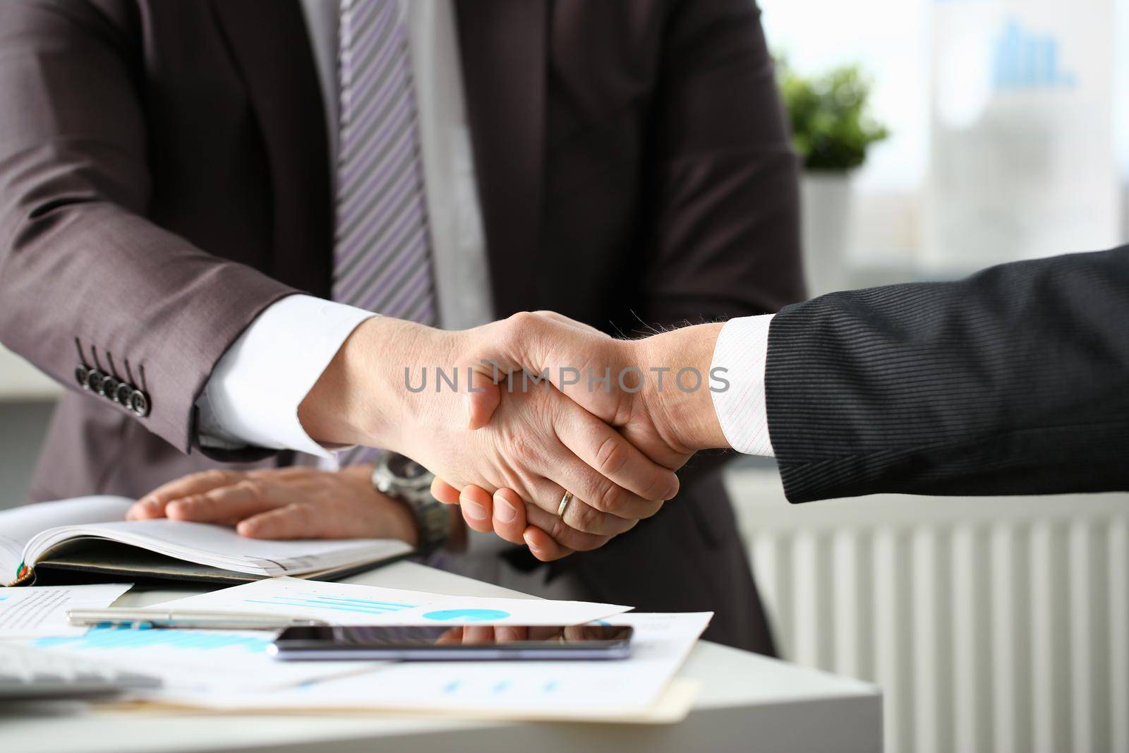 Man in suit shake hand as hello in office by kuprevich