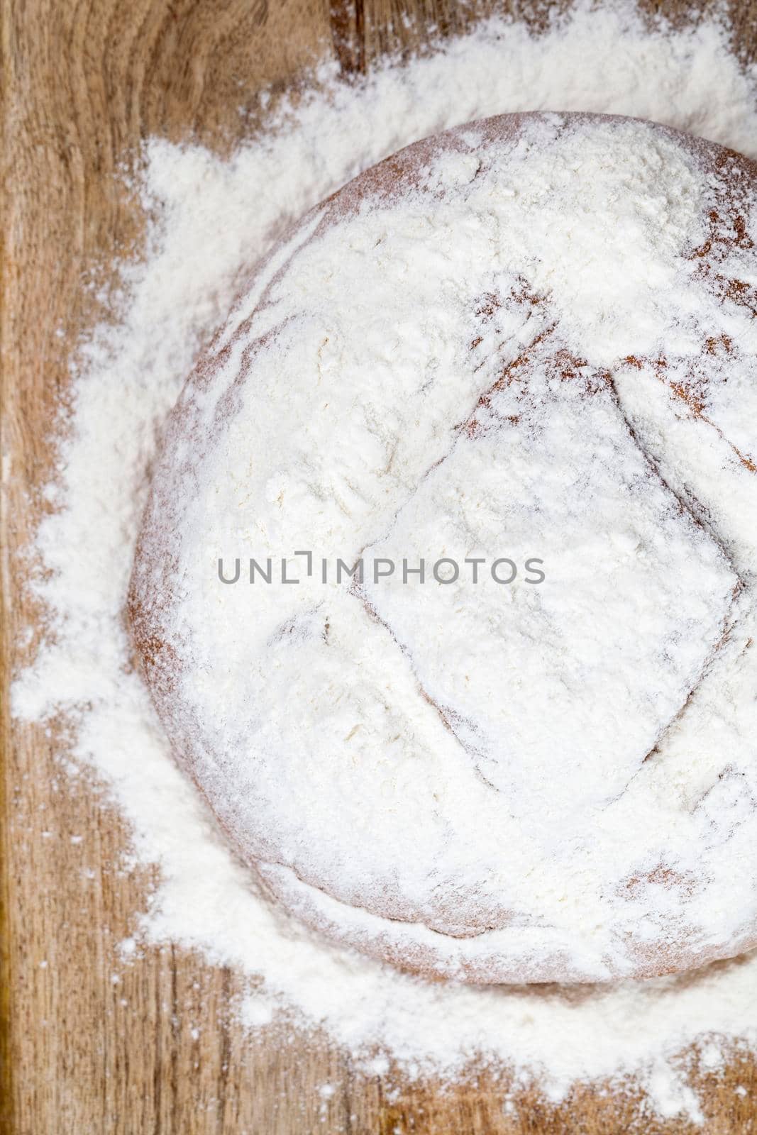 sprinkled with white flour homemade fresh bread lying on a wooden board. photo close-up, top view