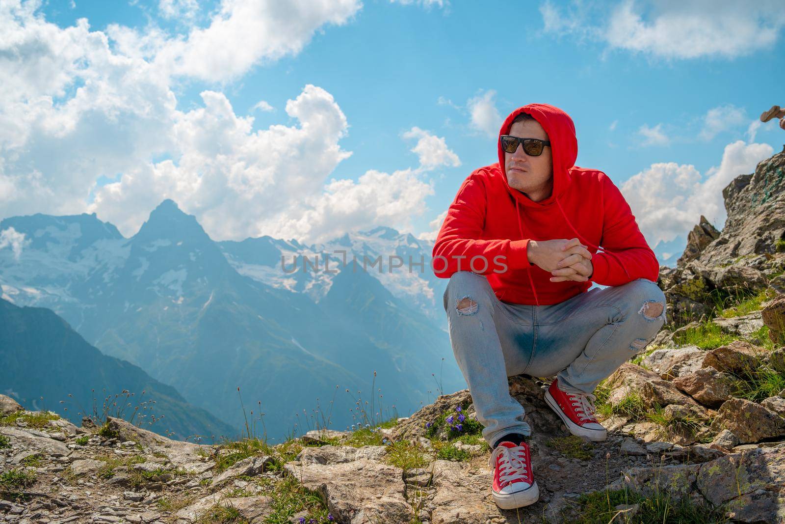 Adult male in red hoodie with hood enjoying beautiful view in mountainous area. by epidemiks