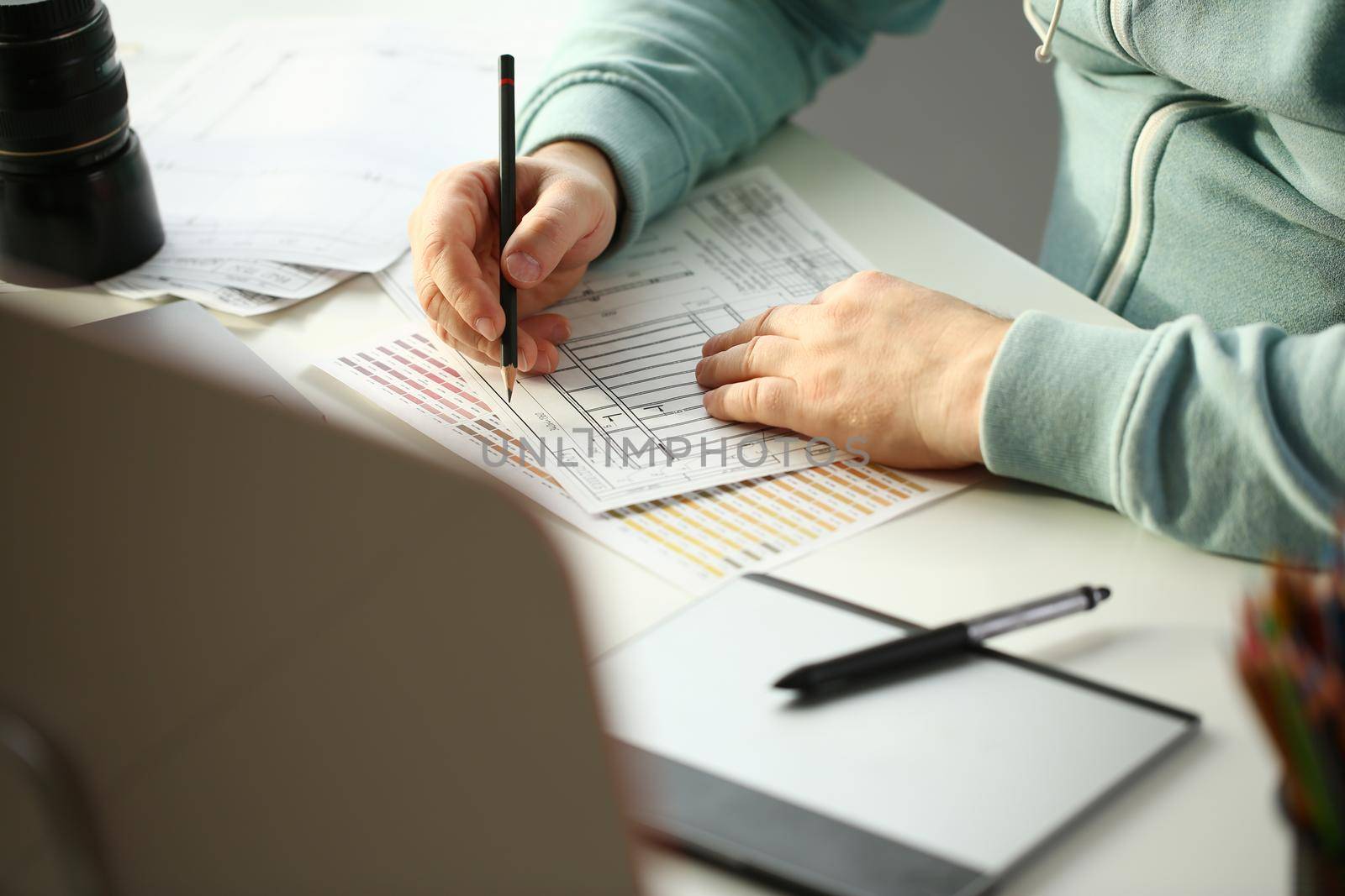 A young designer holds pen from tablet in hand working on new project for customer in field of building construction projects.