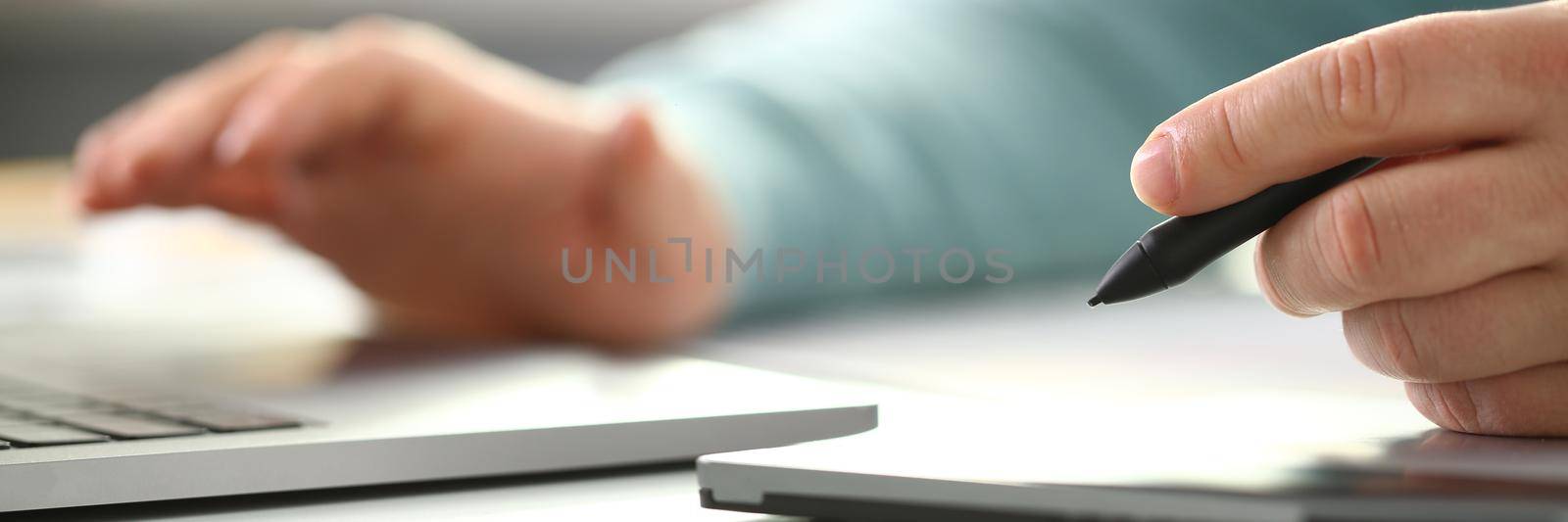 A young designer holds pen from tablet in hand working on new project for customer in field of building construction projects.