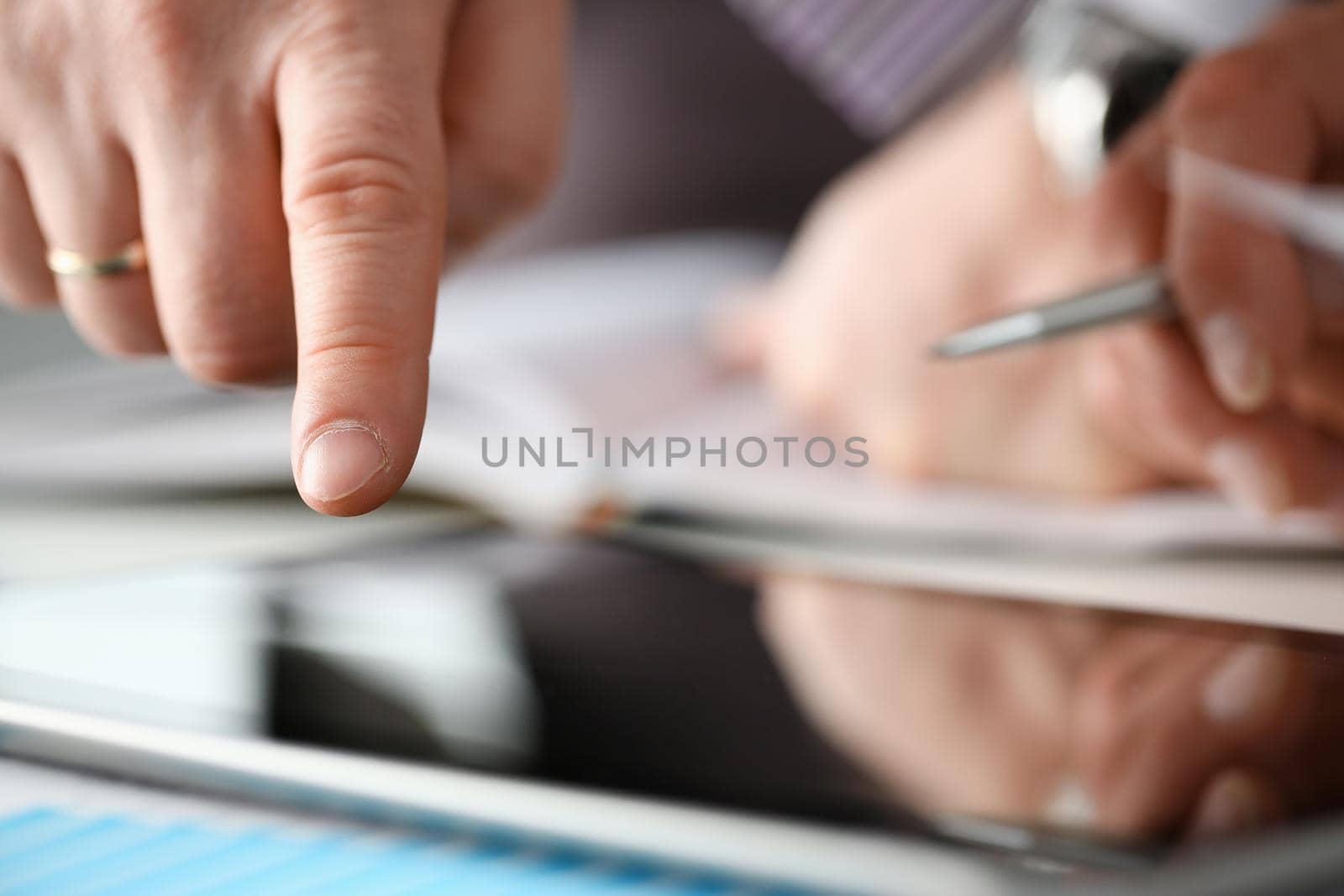 Two businessman are looking and studying statistics on tablet display closeup. Male hand opponent holds pen and points out problem collaboration business coach cooperation partnership palm concept