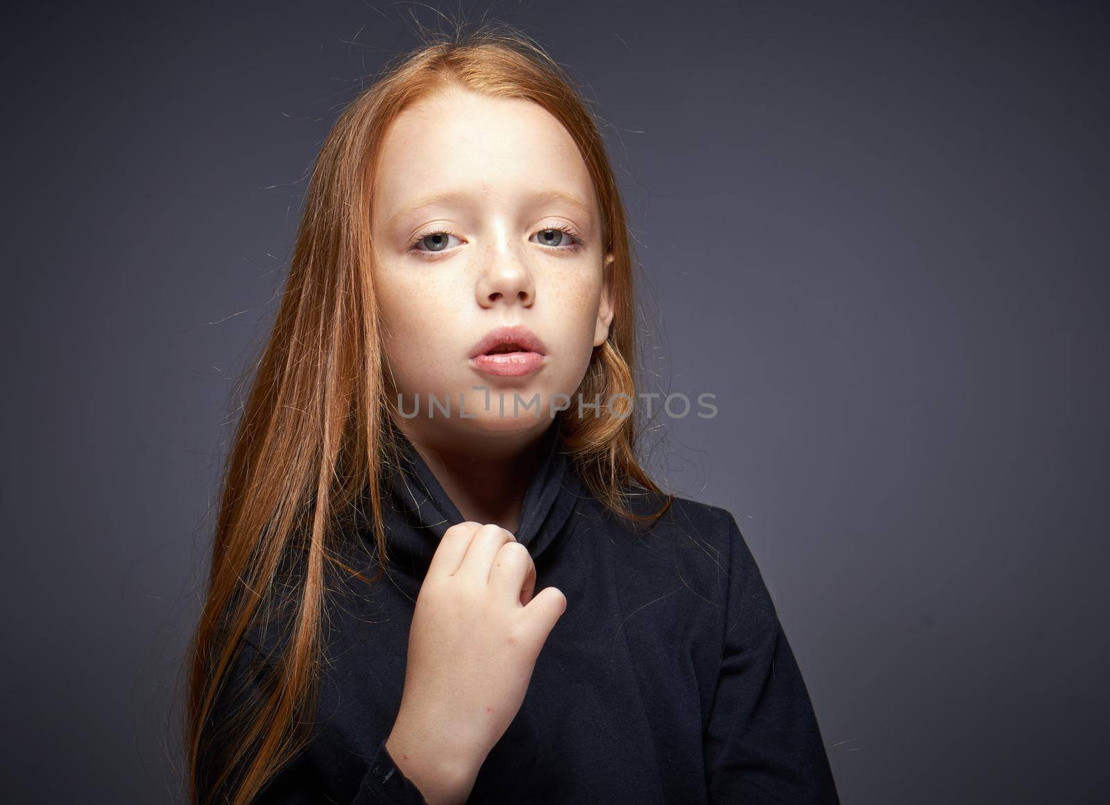 red-haired girl with freckles on her face in a black sweater posing. High quality photo