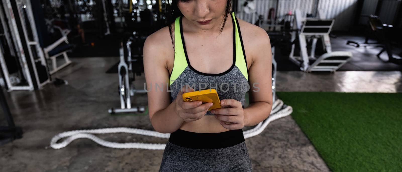 close up young fit woman using smart phone at gym.