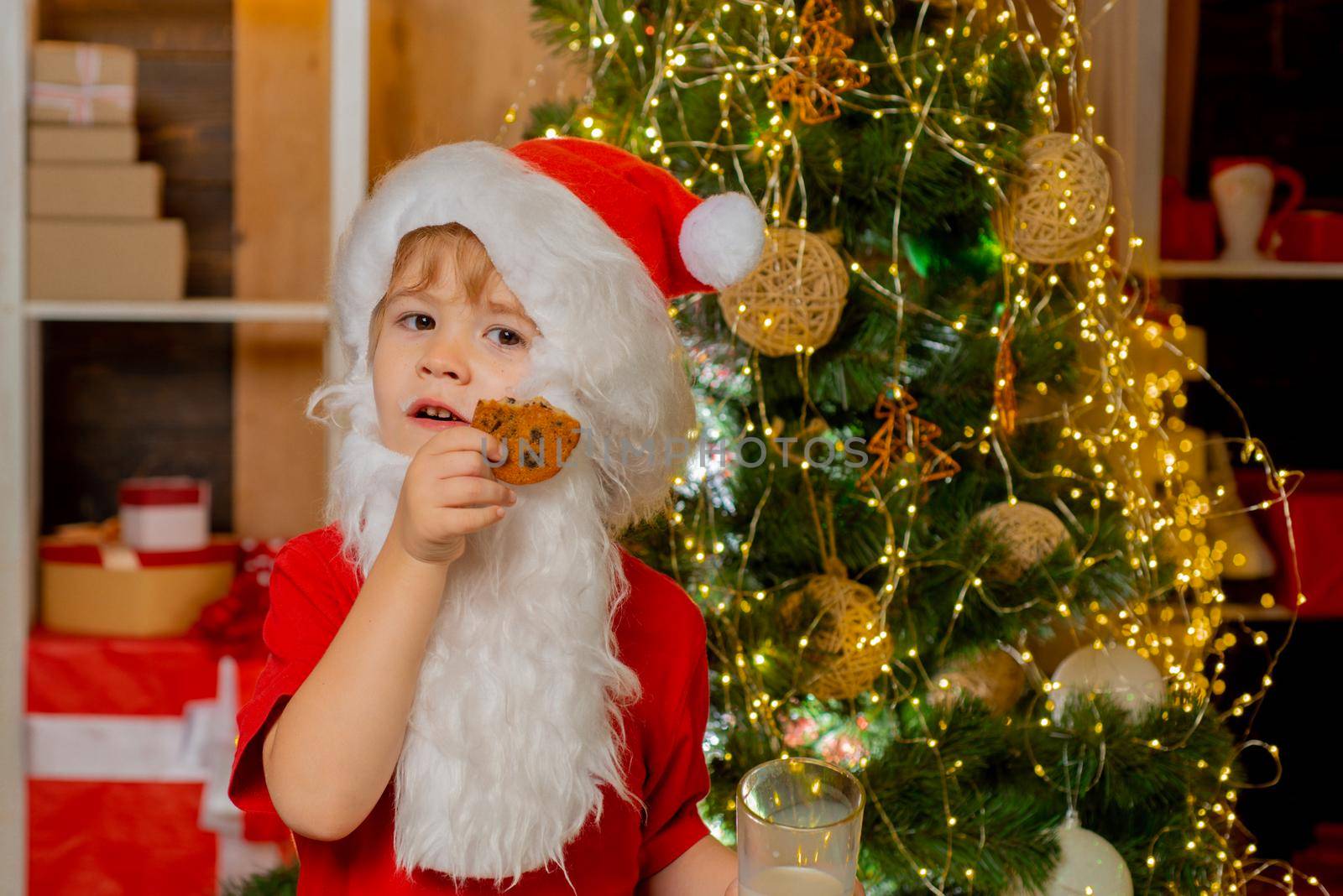 Merry Christmas and happy new year. Thanksgiving day and Christmas. Happy Santa Claus - cute boy child eating a cookie and drinking glass of milk at home Christmas interior