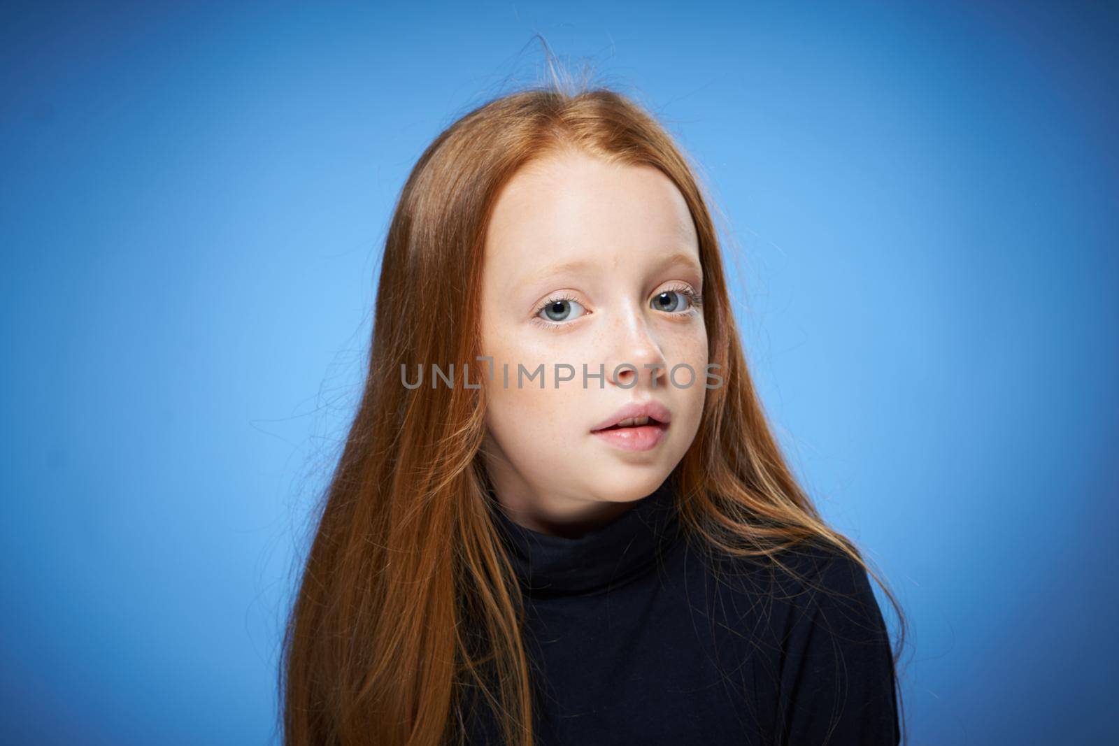 redhead girl with freckles on her face posing close-up blue background. High quality photo