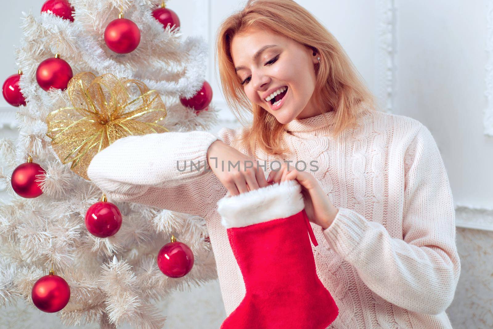 Woman with Christmas Sock, Christmas stockings. Young wife with christmas present boxes in front of christmas tree. Happy new year