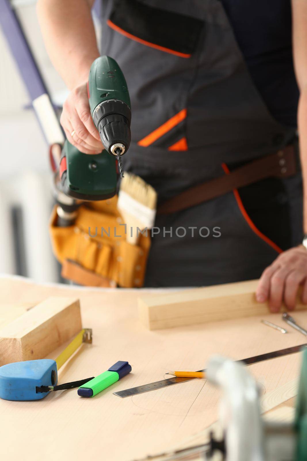 Arms of worker using electric drill closeup by kuprevich