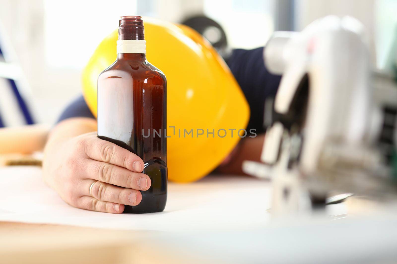 Arm of drunken worker in yellow helmet hold liquor bottle portrait. Manual job workplace DIY inspiration fix shop hard hat industrial education profession career