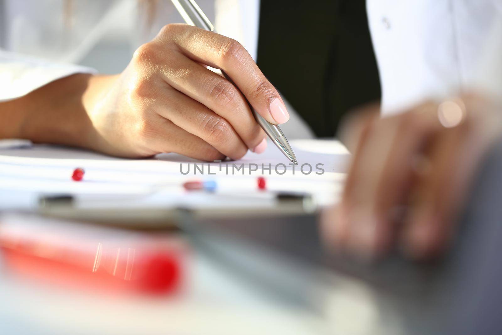 Female medicine doctor hand hold siver pen and write prescription to patient at worktable. Panacea and life save, prescribing treatment, legal drug store concept. Empty form ready to be used