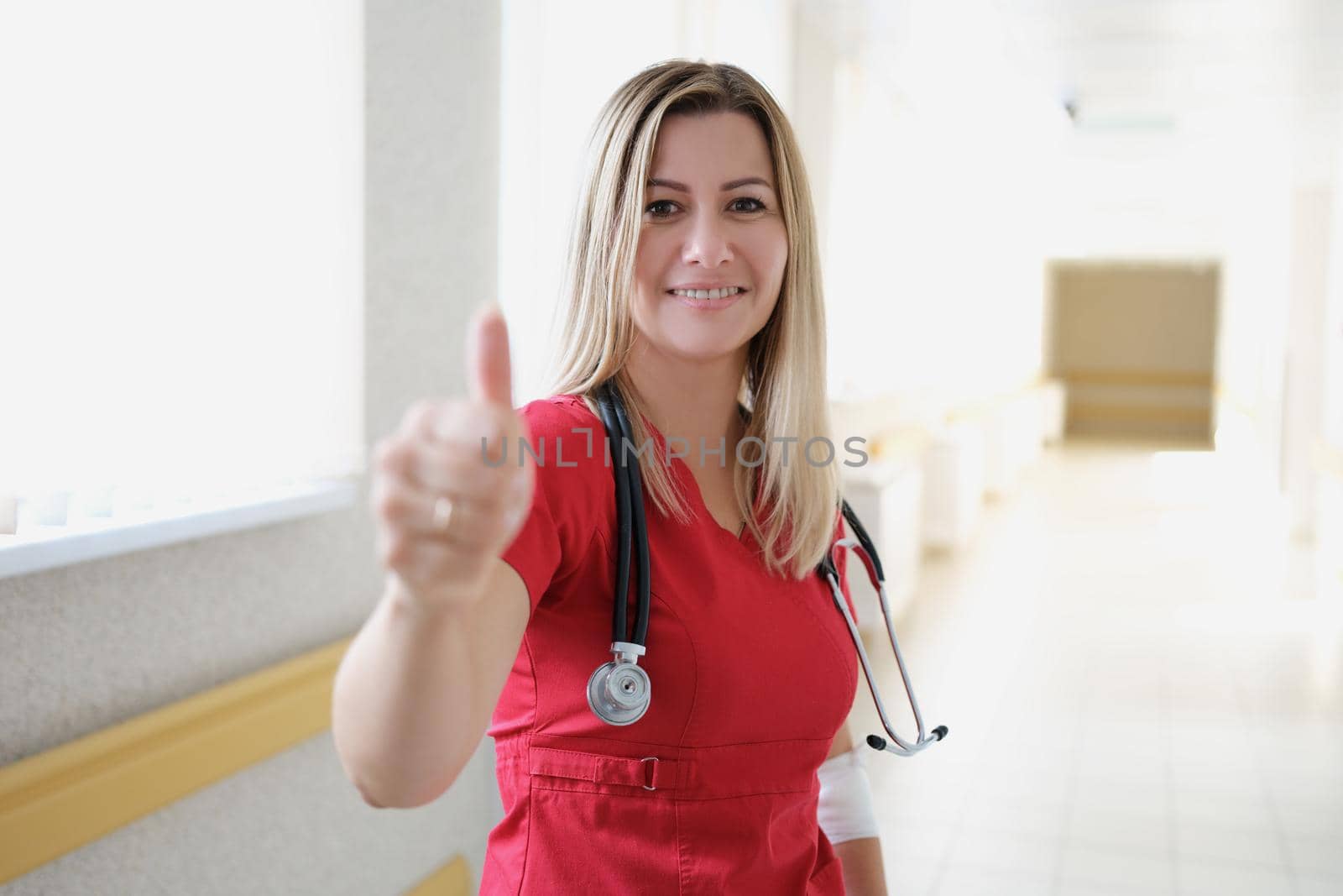 Young female doctor with stethoscope showing thumb up by kuprevich