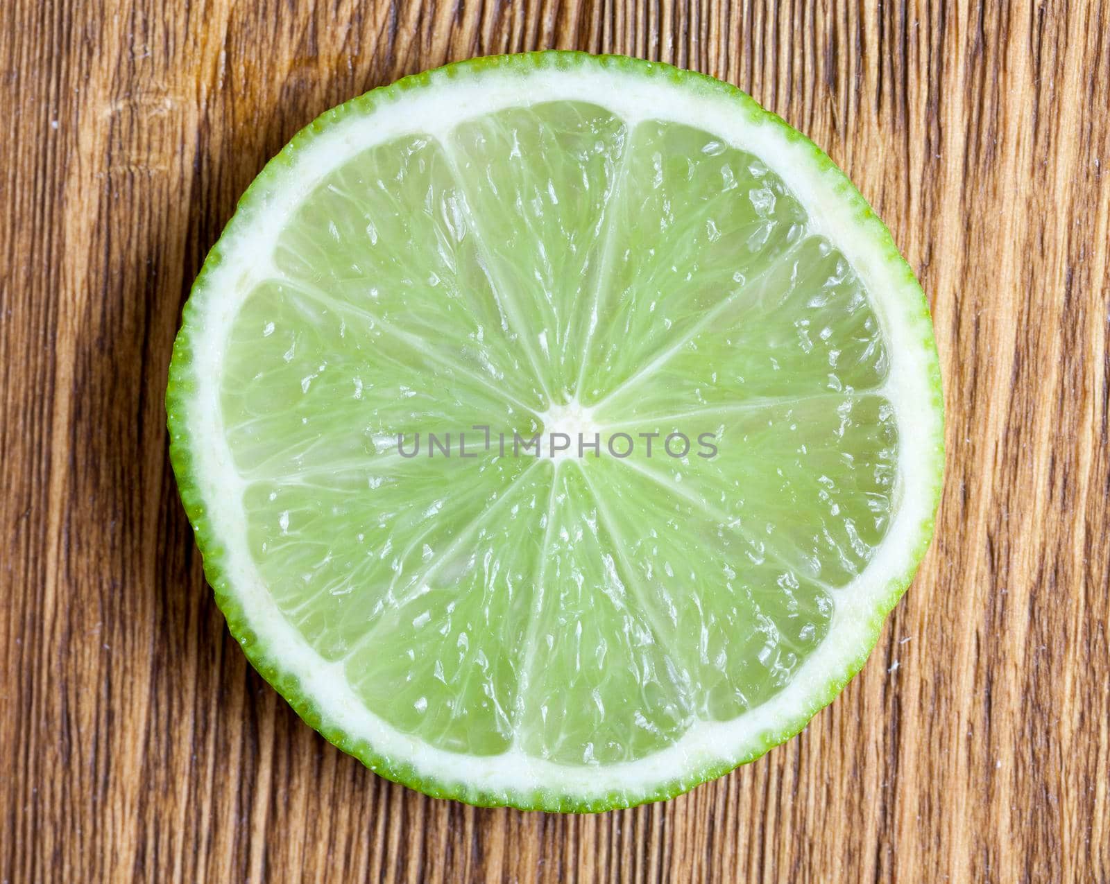 cut across the green lime, laid on a wooden table, closeup of a citrus food, top