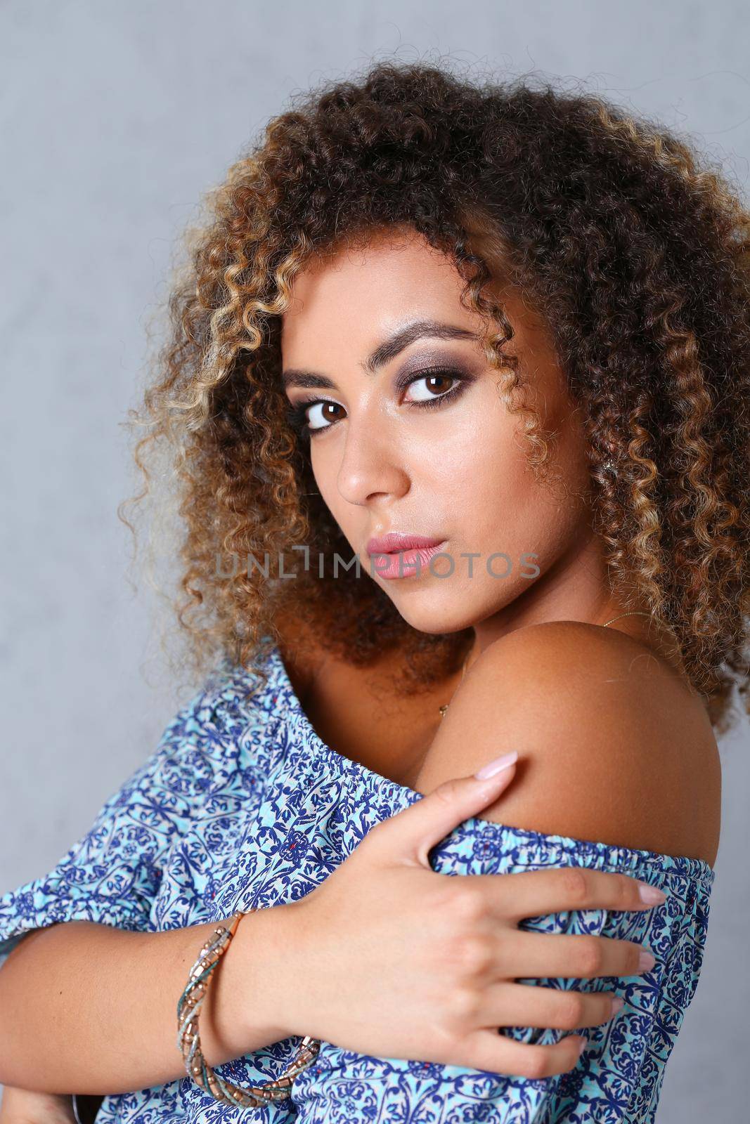 Beautiful black woman portrait. Worth a gray background and smiling beauty fashion style curly hair with white strands view of the eye in the camera