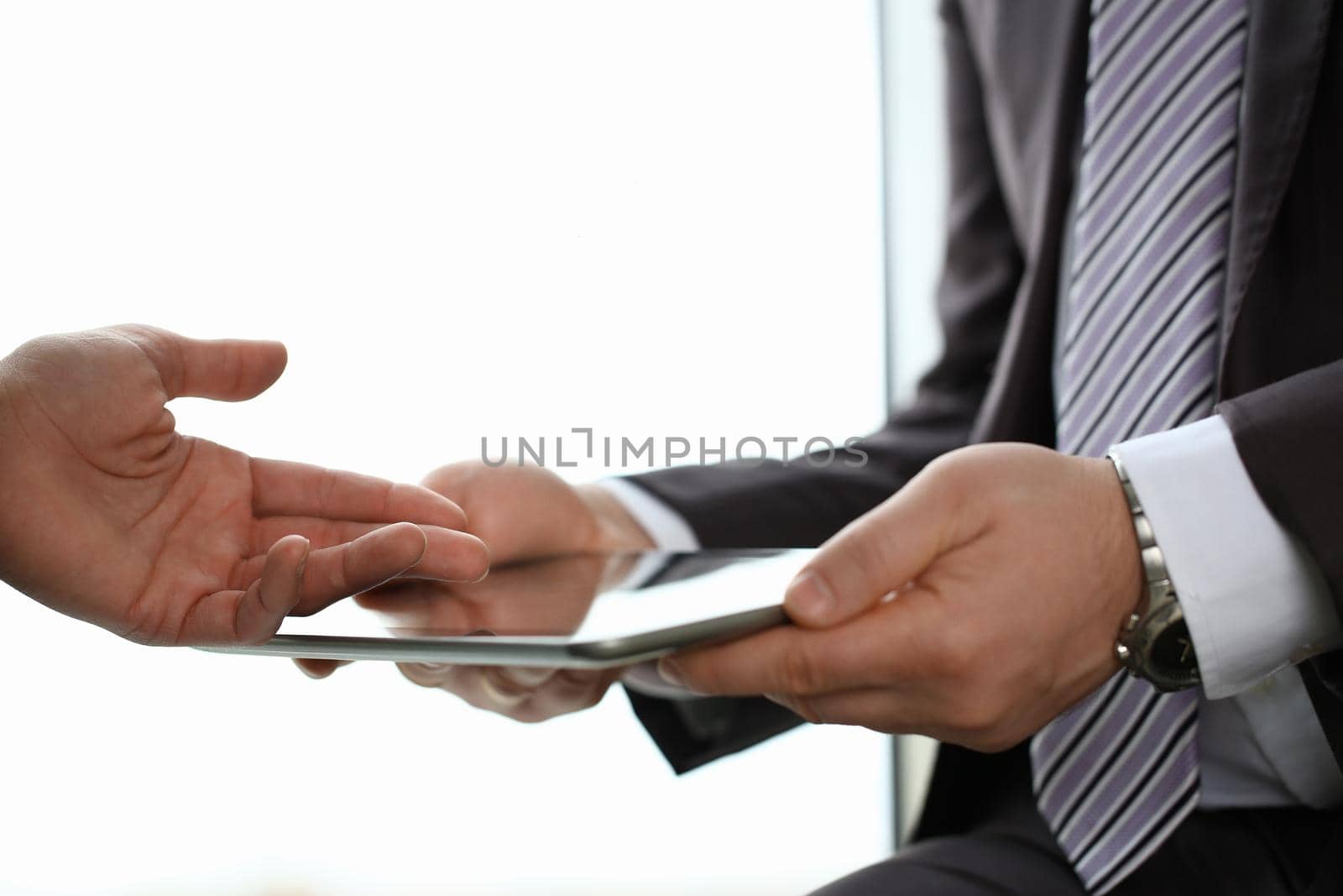 Two businessman are looking and studying statistics on tablet display closeup. Male hand opponent holds pen and points out problem collaboration business coach cooperation partnership palm concept