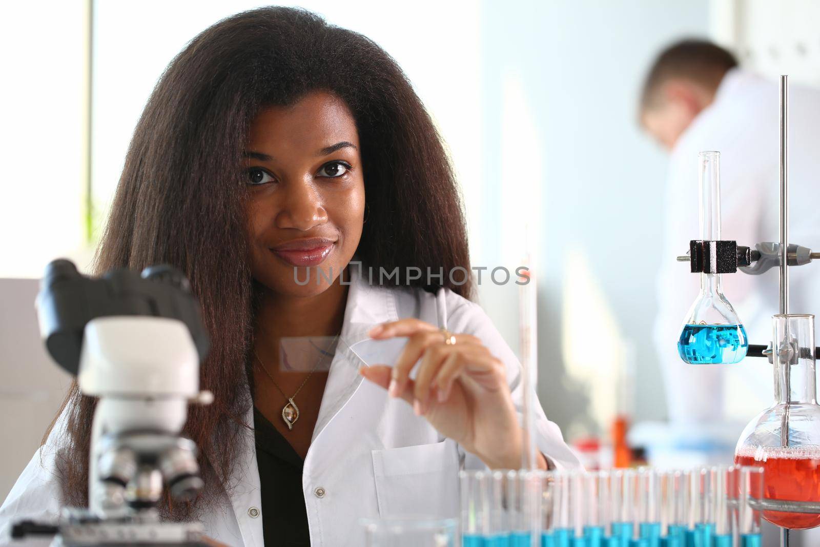 A female chemist holds test tube of glass in his hand overflows liquid solution potassium permanganate conducts an analysis reaction takes various versions reagents using chemical manufacturing.