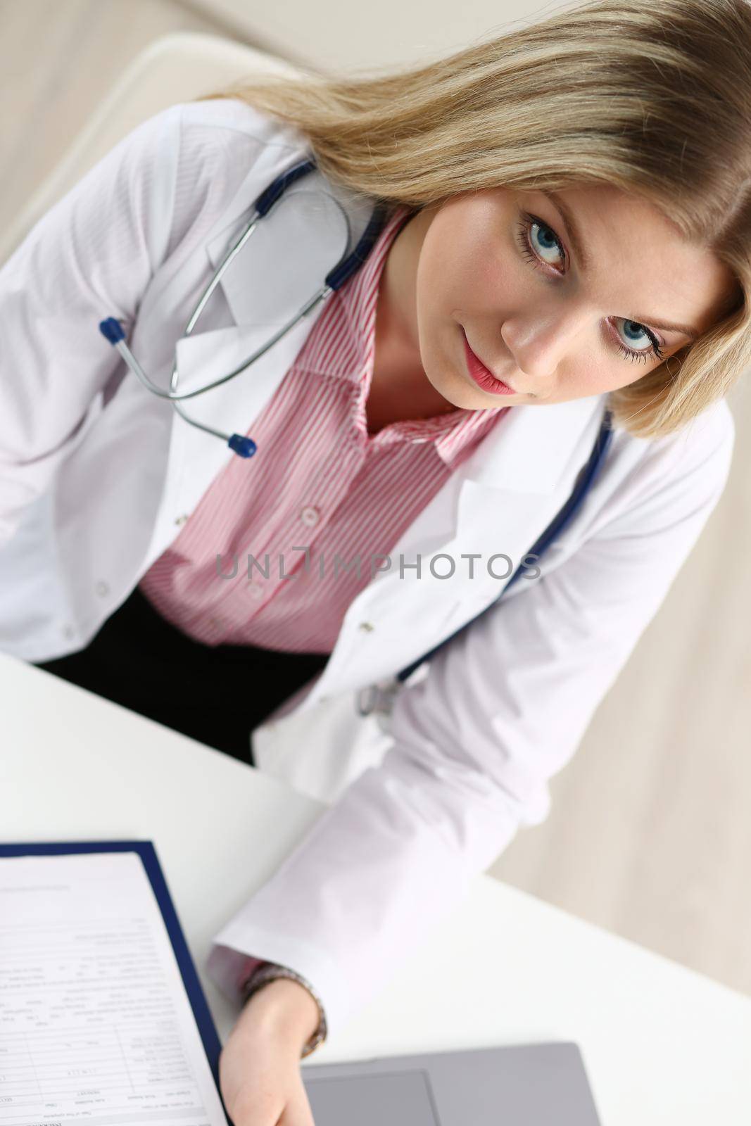 Beautiful smiling female doctor hold clipboard pad and fill something with silver pen. Physical illness prevention prescribe remedy ward round therapeutist assistance healthy lifestyle concept