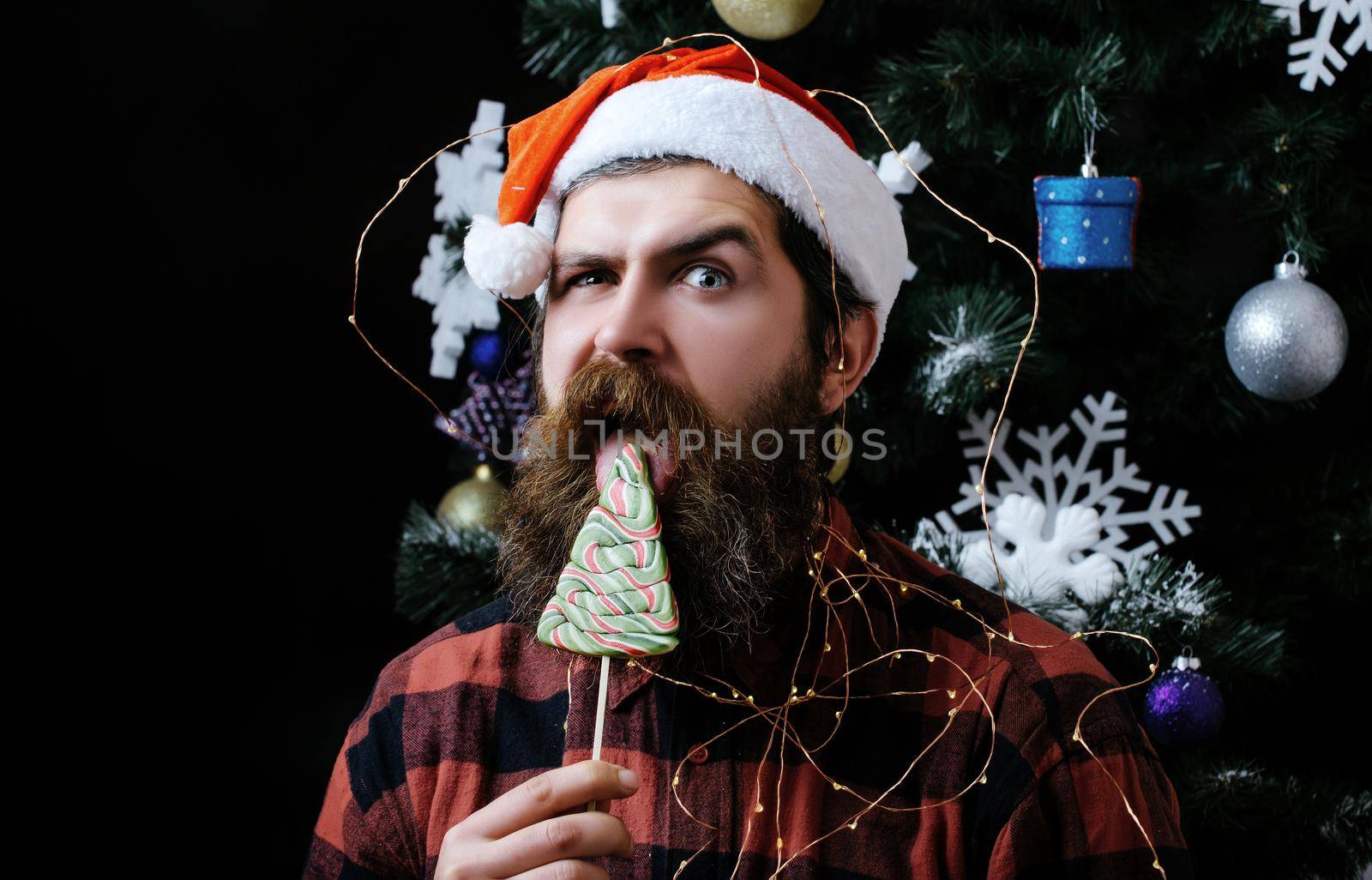 Funny man with beard on surprised face and lollipop. New year guy lick candy or sweet. Winter holiday and xmas. Party celebration and blowjob. Bearded handsome man, Santa Claus with beard