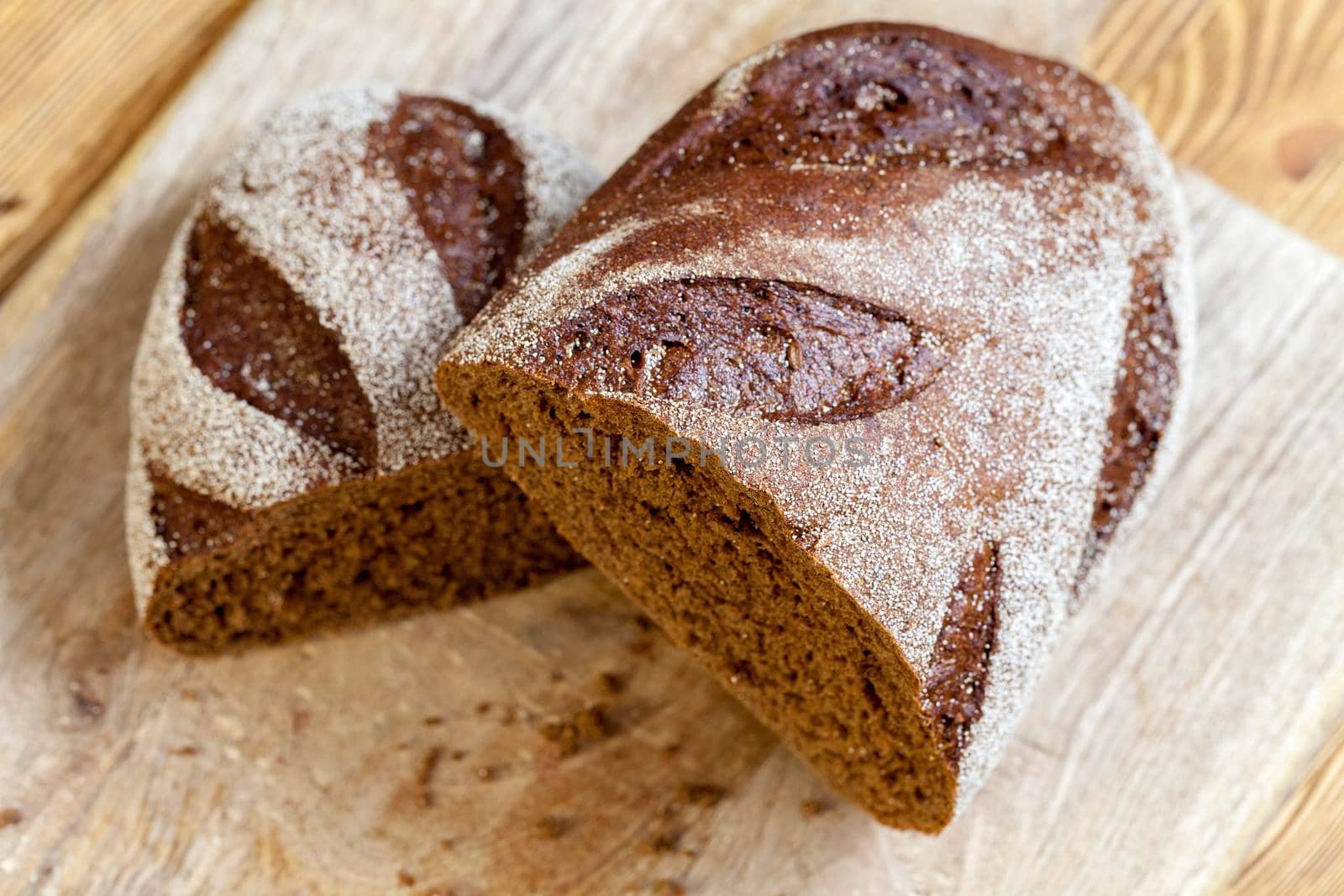 Two halves of black aromatic bread baked from rye flour. The loaf is cut into two halves during cooking. Photo close up