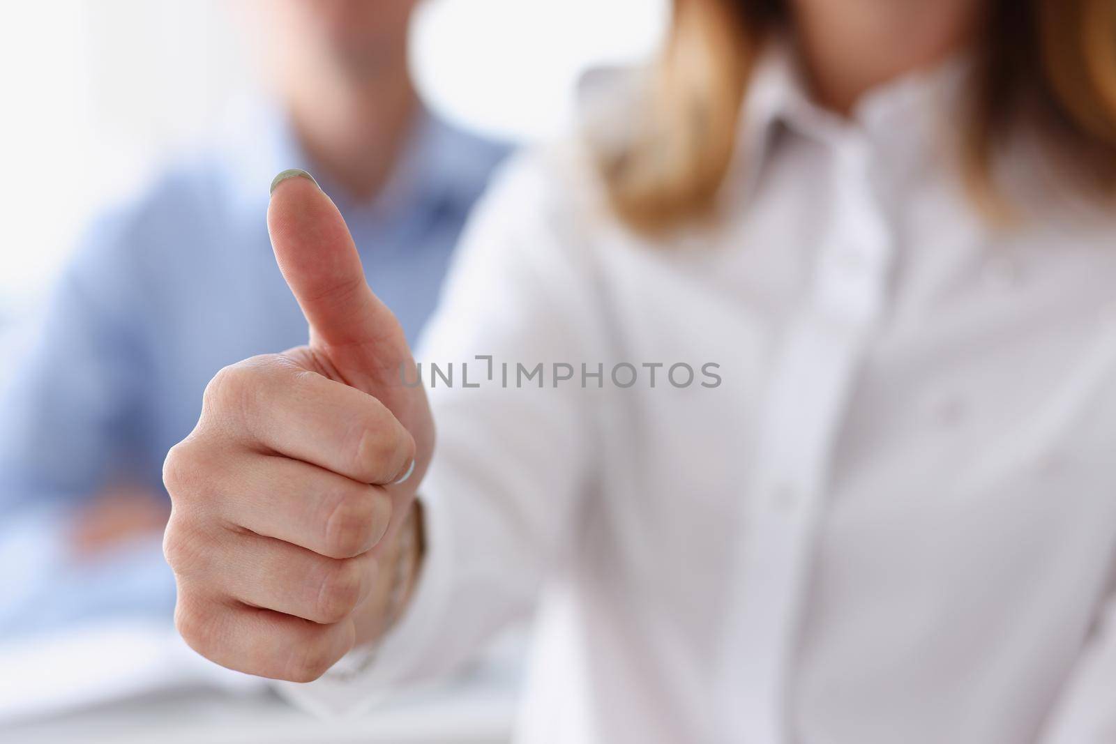 Female hand showing ok or approval sign with thumb up in creative people office during conference. High level and quality service job offer excellent education advisor serious business concept okay