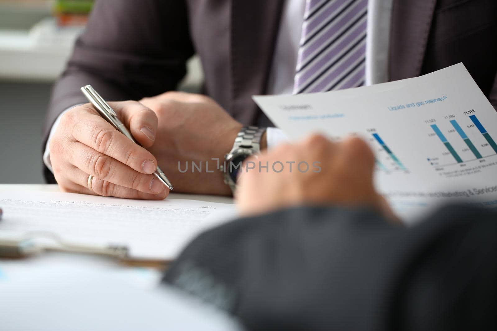 Male arm in suit and tie fill form clipped pad with silver pen closeup. Sign gesture read pact sale agent bank job make note loan credit mortgage investment finance executive chief legal teamwork law