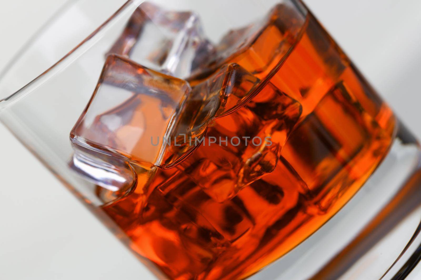 Whiskey with ice in glass beaker on gray background