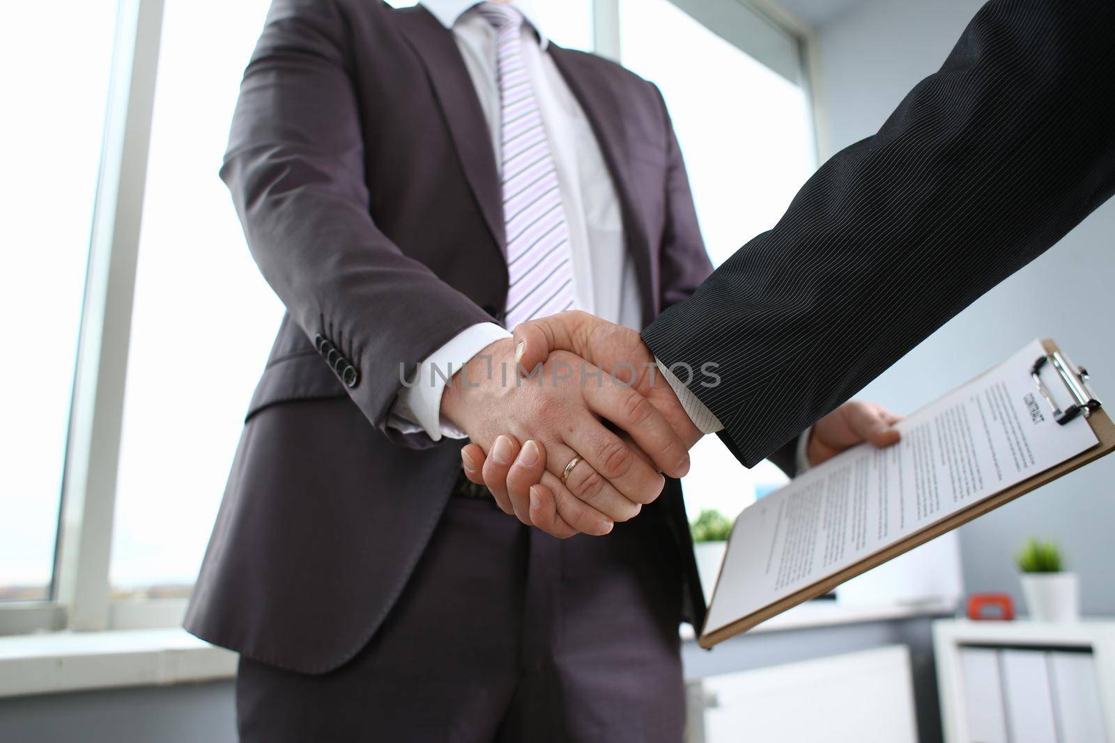 Man in suit shake hand as hello in office by kuprevich