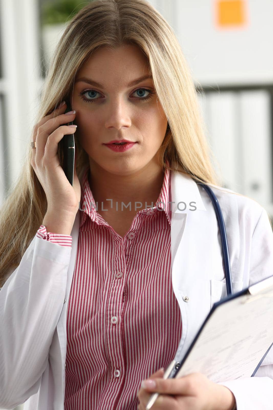 Beautiful female blond doctor talking on phone by kuprevich