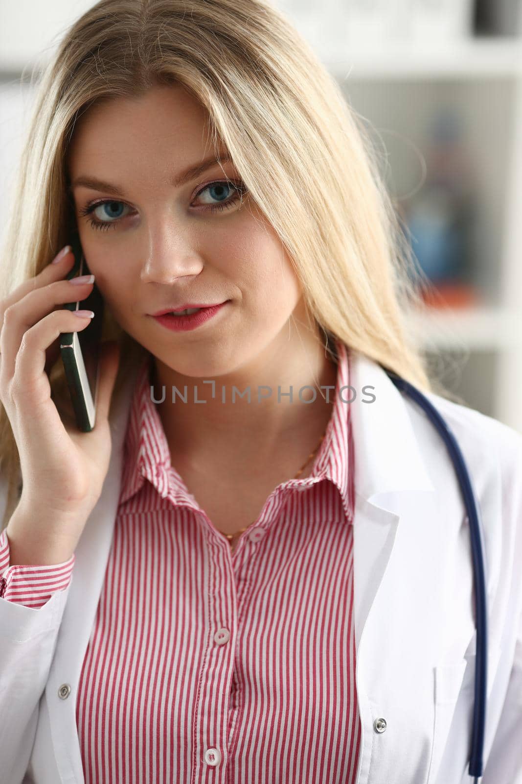 Beautiful female blond doctor talking on phone at the office woman discussing the disease and giving online consultation remote training education