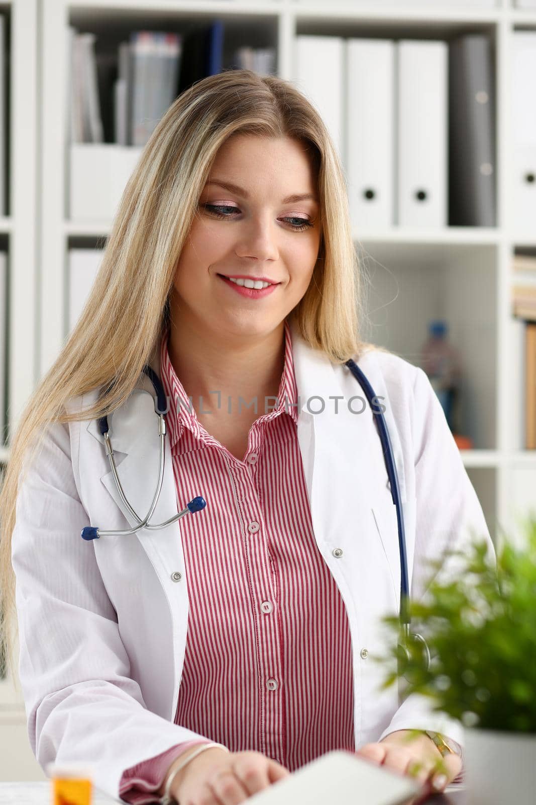 Beautiful smiling female doctor sit at workplace by kuprevich