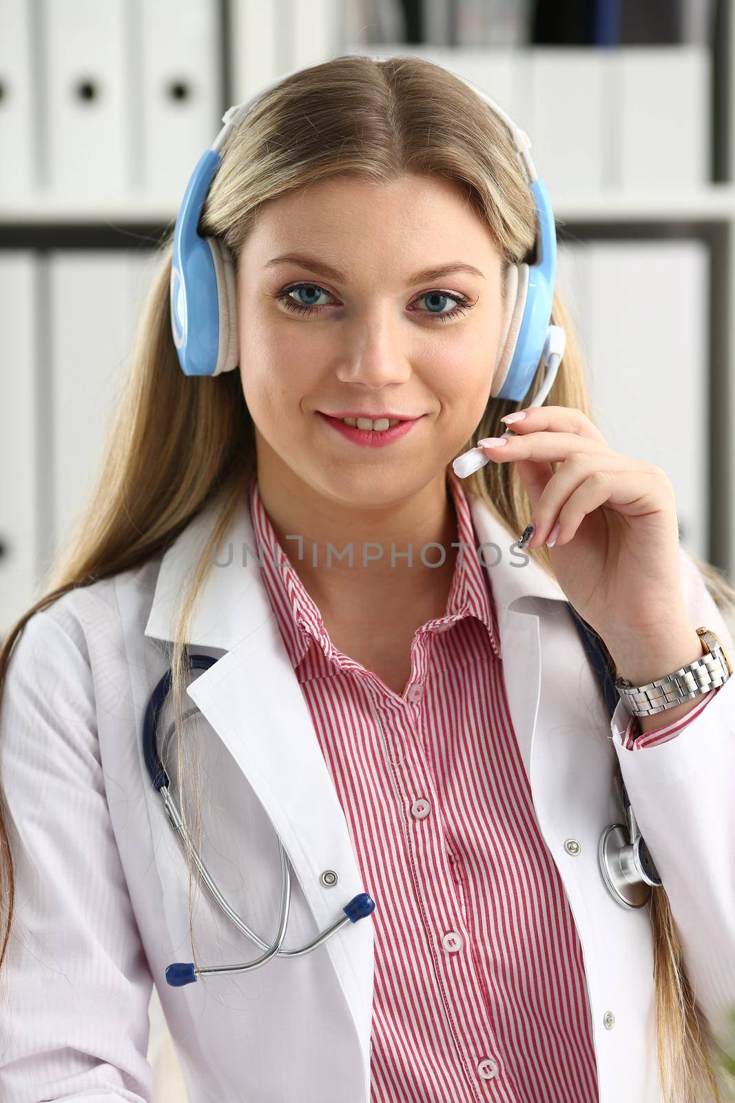 A beautiful feminine blonde doctor talking to patient over wireless headset advises a medical problem the formation of remote education internship callcenter specialist