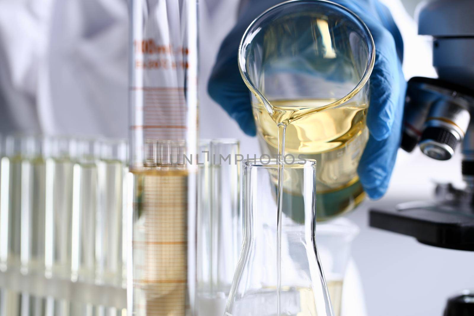 Male hand hold yellow liquid in test tube. Conveyor line production household cleaning products detergents help cleaning destruction stains pests urine poison antidote vaccine concept.