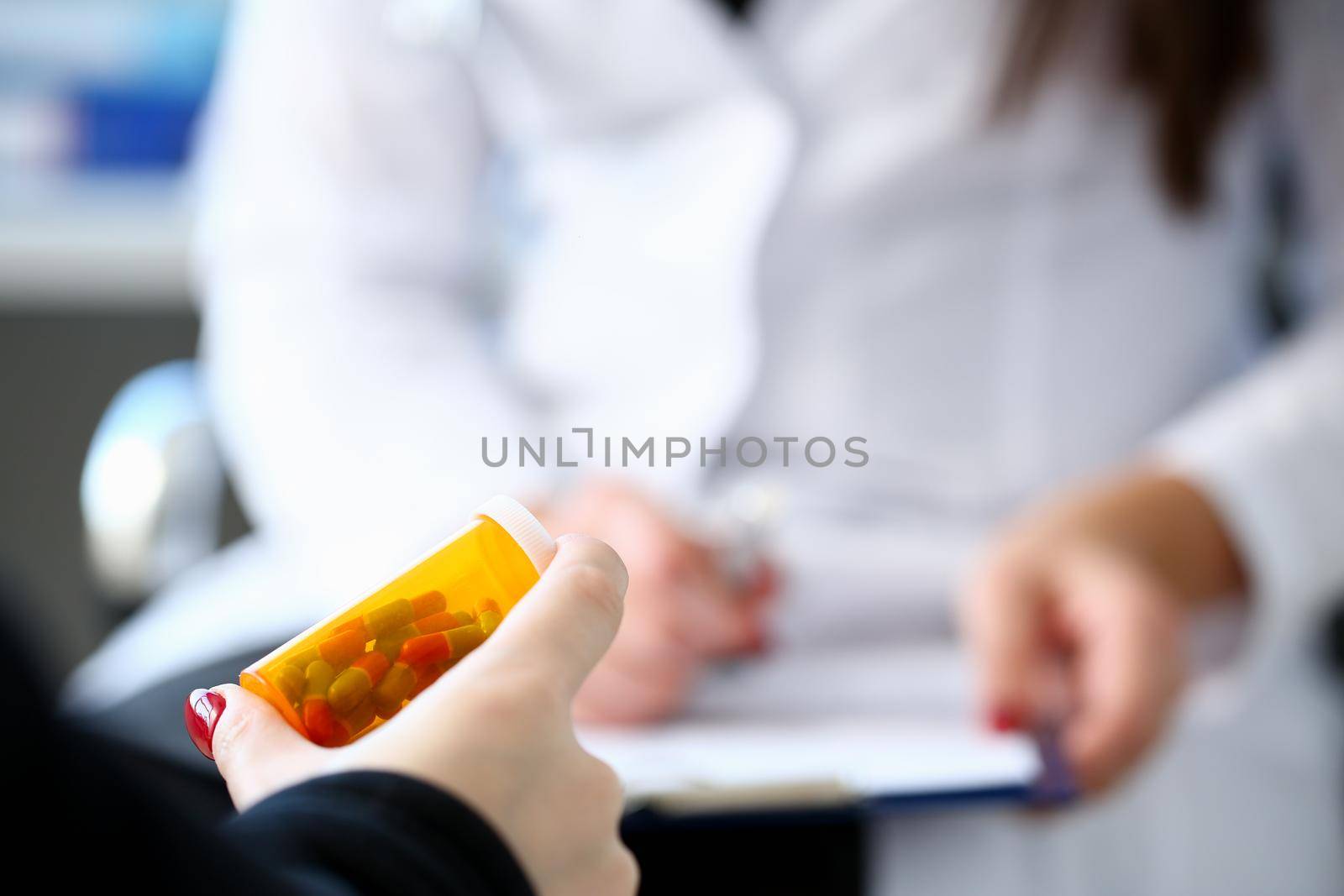 Female medicine doctor hand hold jar of pills by kuprevich