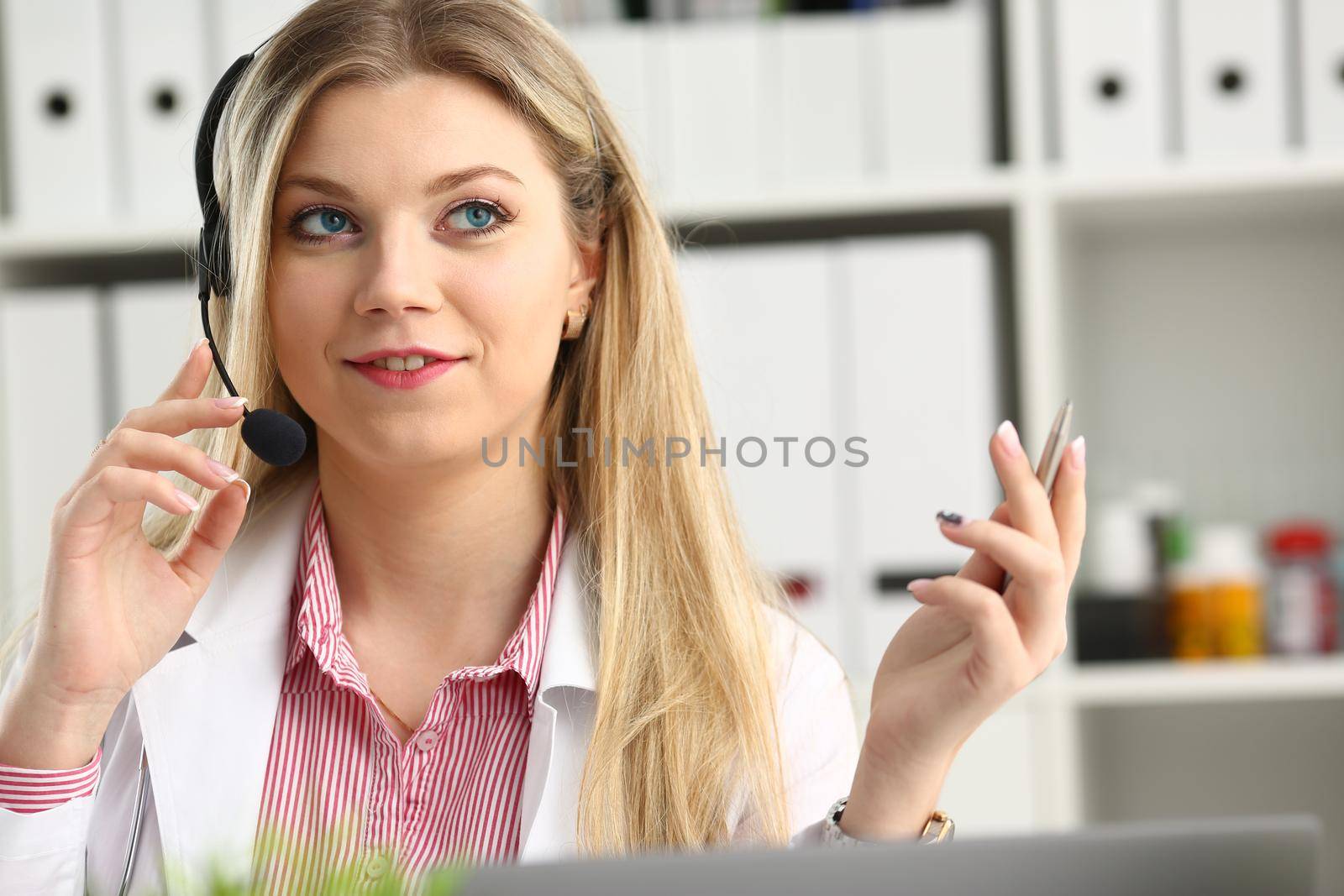 A beautiful feminine blonde doctor talking to patient over wireless headset advises a medical problem the formation of remote education internship callcenter specialist