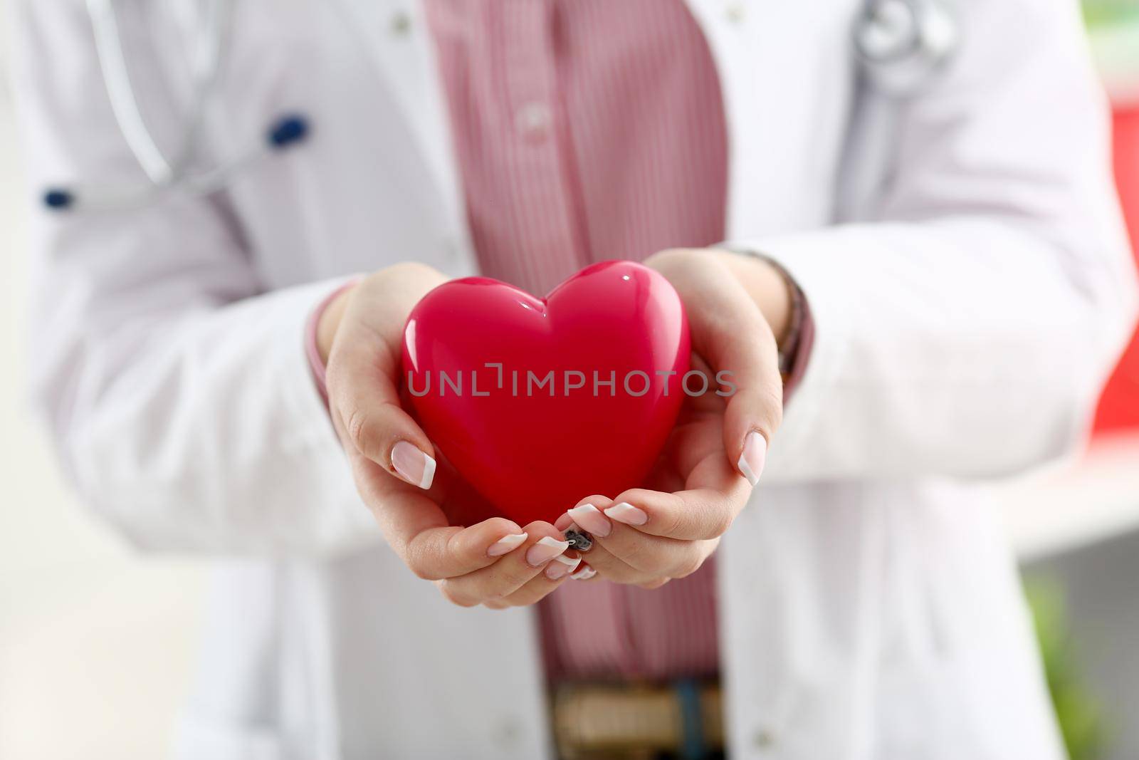 Female doctor hold in arms and cover red toy heart closeup. Cardio therapeutist student education CPR 911 life save physician make cardiac physical pulse rate measure arrhythmia lifestyle