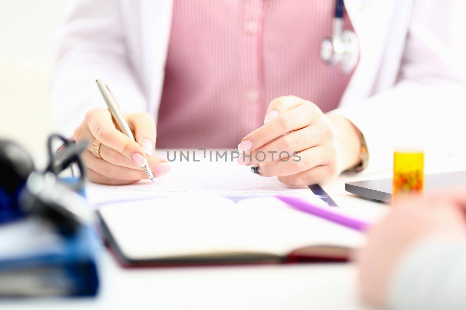 Female medicine doctor hand hold jar of pills and write prescription to patient at worktable. Panacea and life save, prescribing treatment, legal drug store concept. Empty form ready to be used