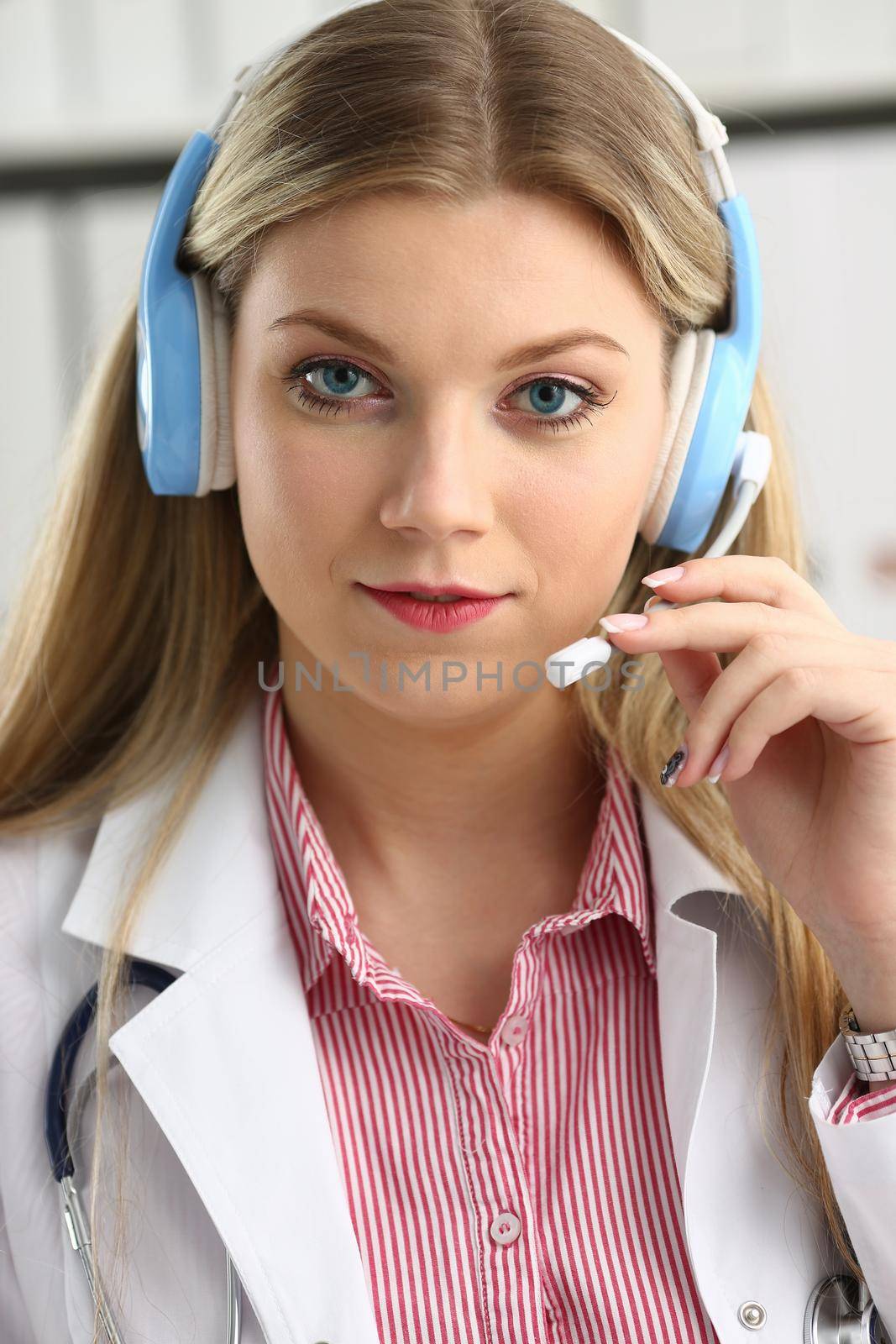 A beautiful feminine blonde doctor talking to patient over wireless headset advises a medical problem the formation of remote education internship callcenter specialist