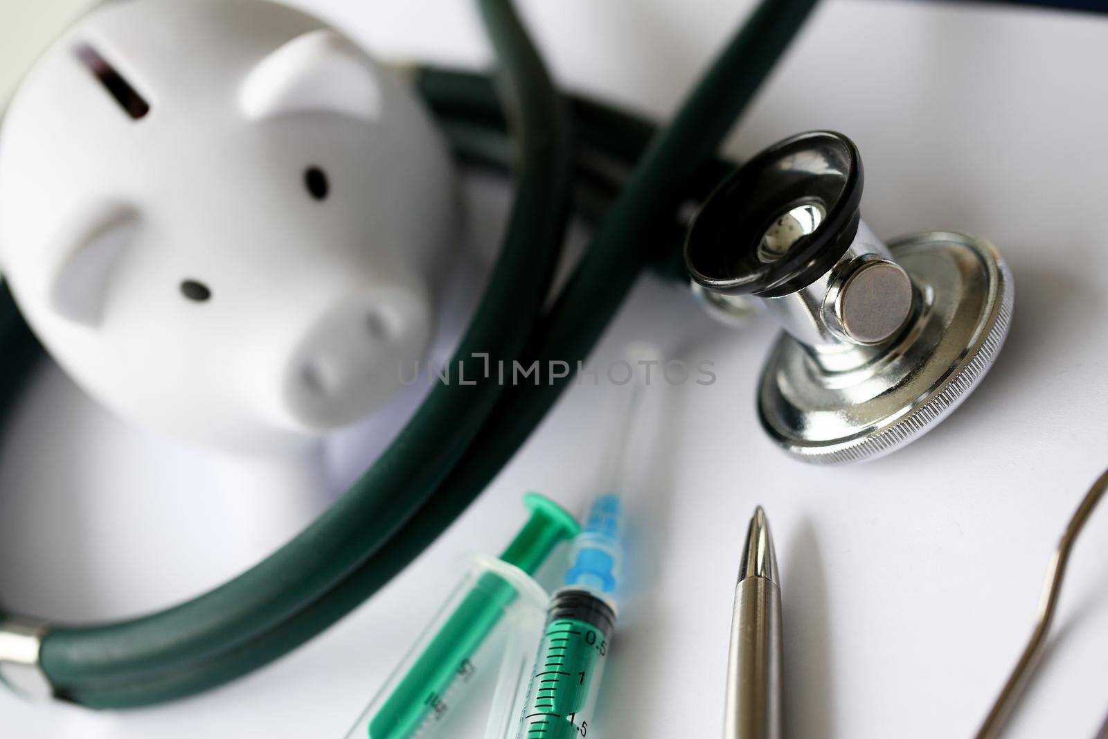 Syringe stethoscope and piggy bank for money on medicine doctor desk health insurance working ability concept