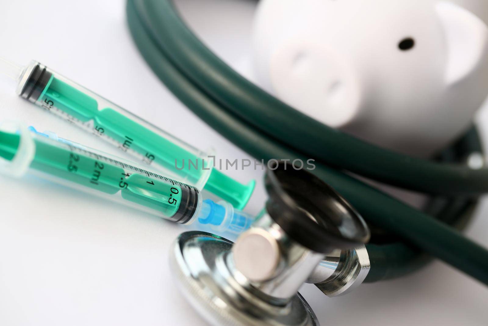 Syringe stethoscope and piggy bank for money on medicine doctor desk health insurance working ability concept