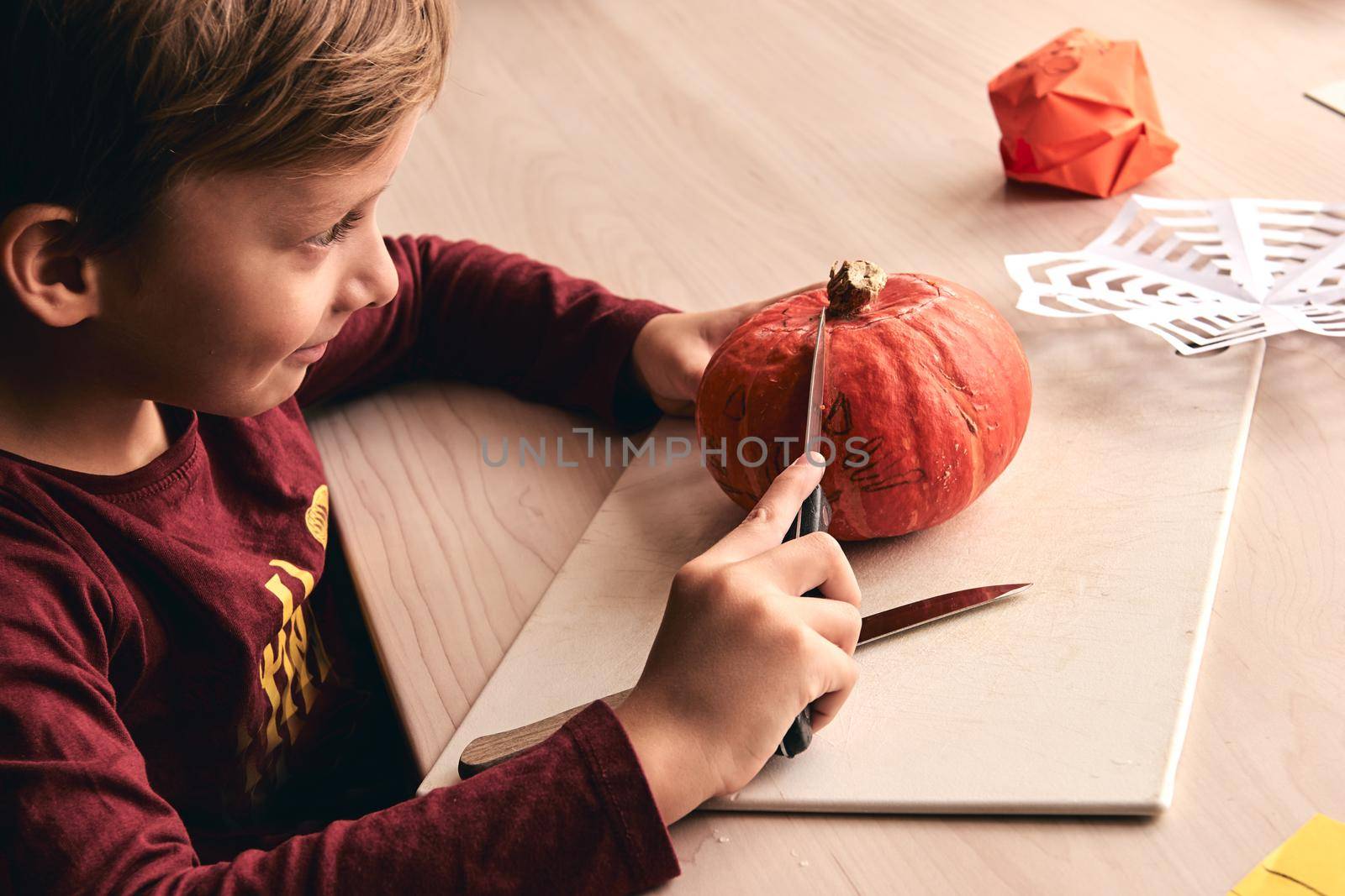 Halloween, decoration and holidays ideas- close up of kid with knife carving pumpkin or jack-o-lantern. 6 years boy has homefamily fun activity. Mom spending time with son together.