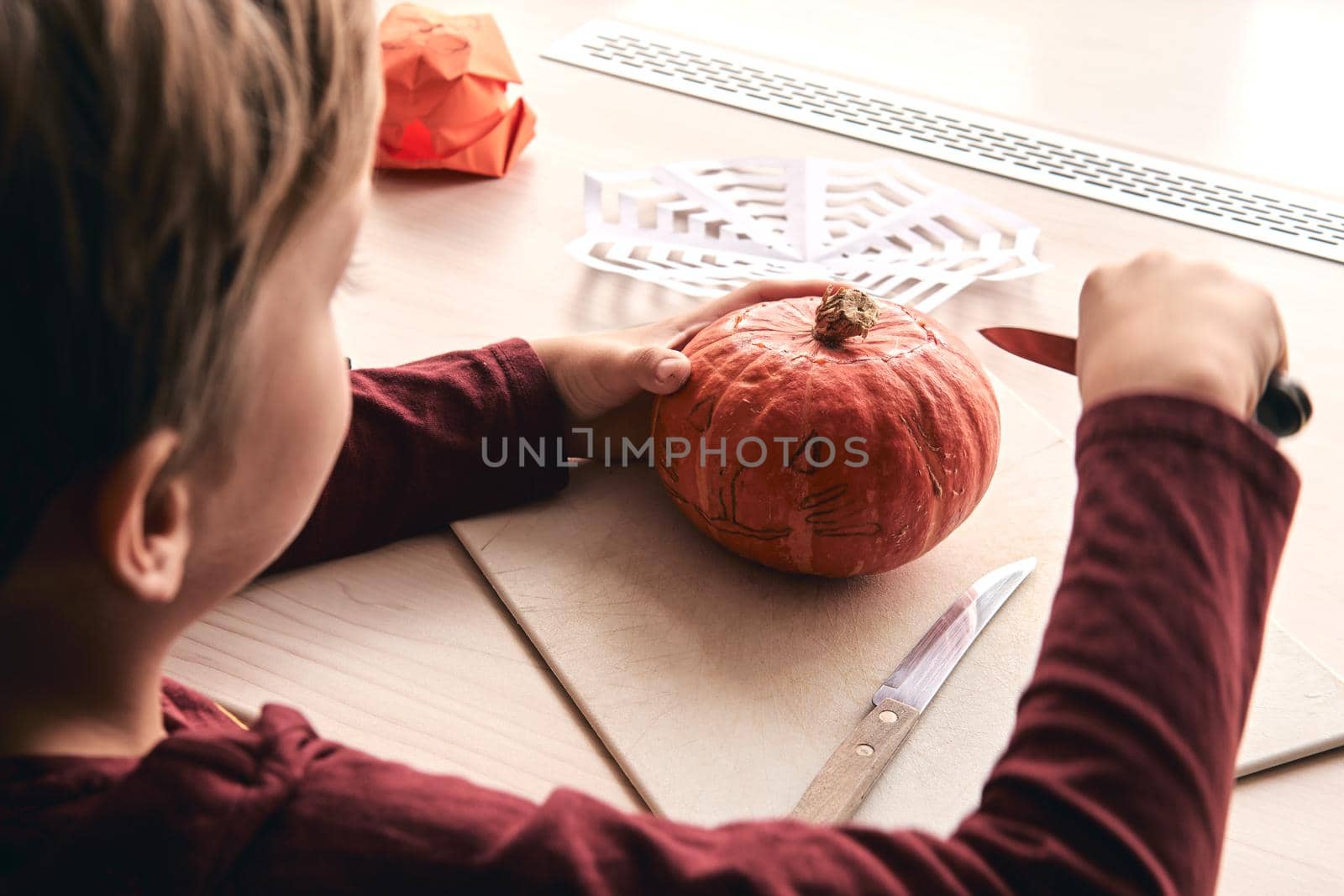 Halloween, decoration and holidays ideas- close up of kid with knife carving pumpkin or jack-o-lantern. 6 years boy has homefamily fun activity. Mom spending time with son together by OneWellStyudio
