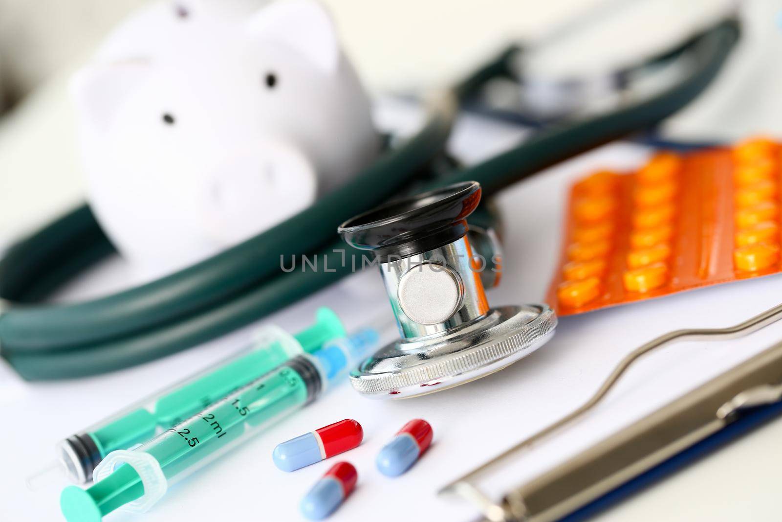 Syringe stethoscope and piggy bank for money on medicine doctor desk health insurance working ability concept