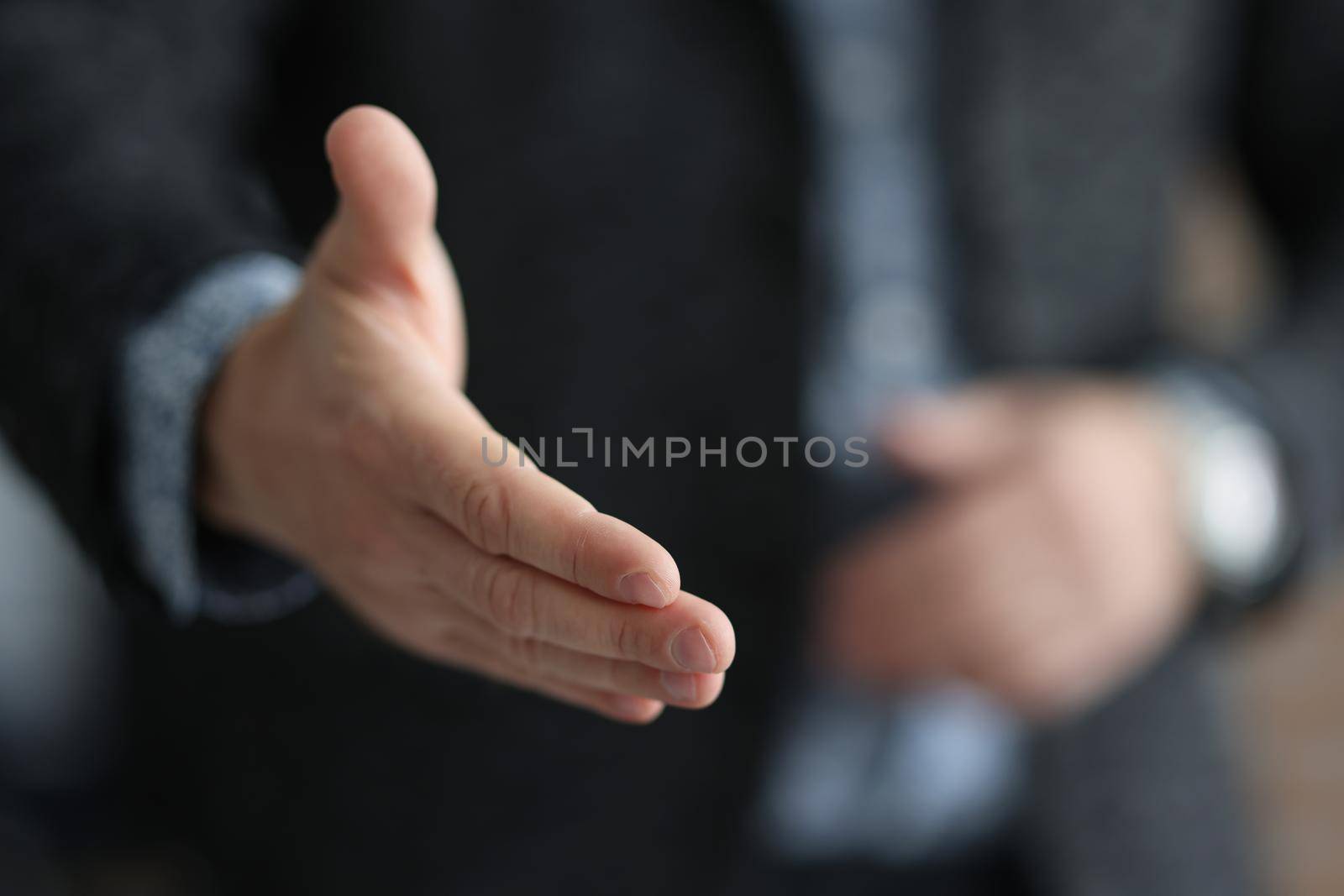 Businessman in suit stretching out his hand for handshake with partner closeup. Profitable deals and projects in business concept