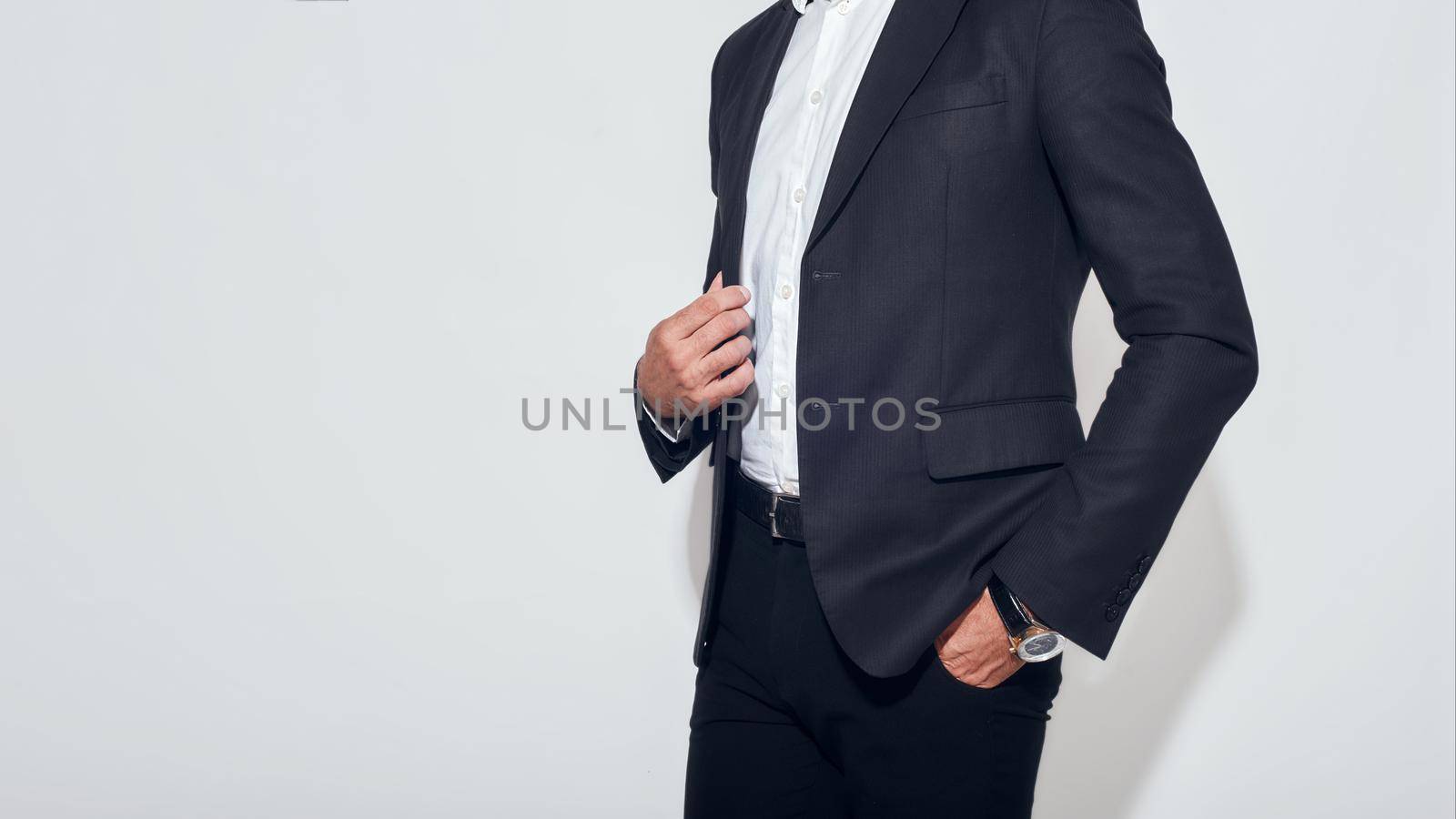 Business look. Cropped portrait of businessman in classic suit adjusting jacket while standing against grey background by friendsstock