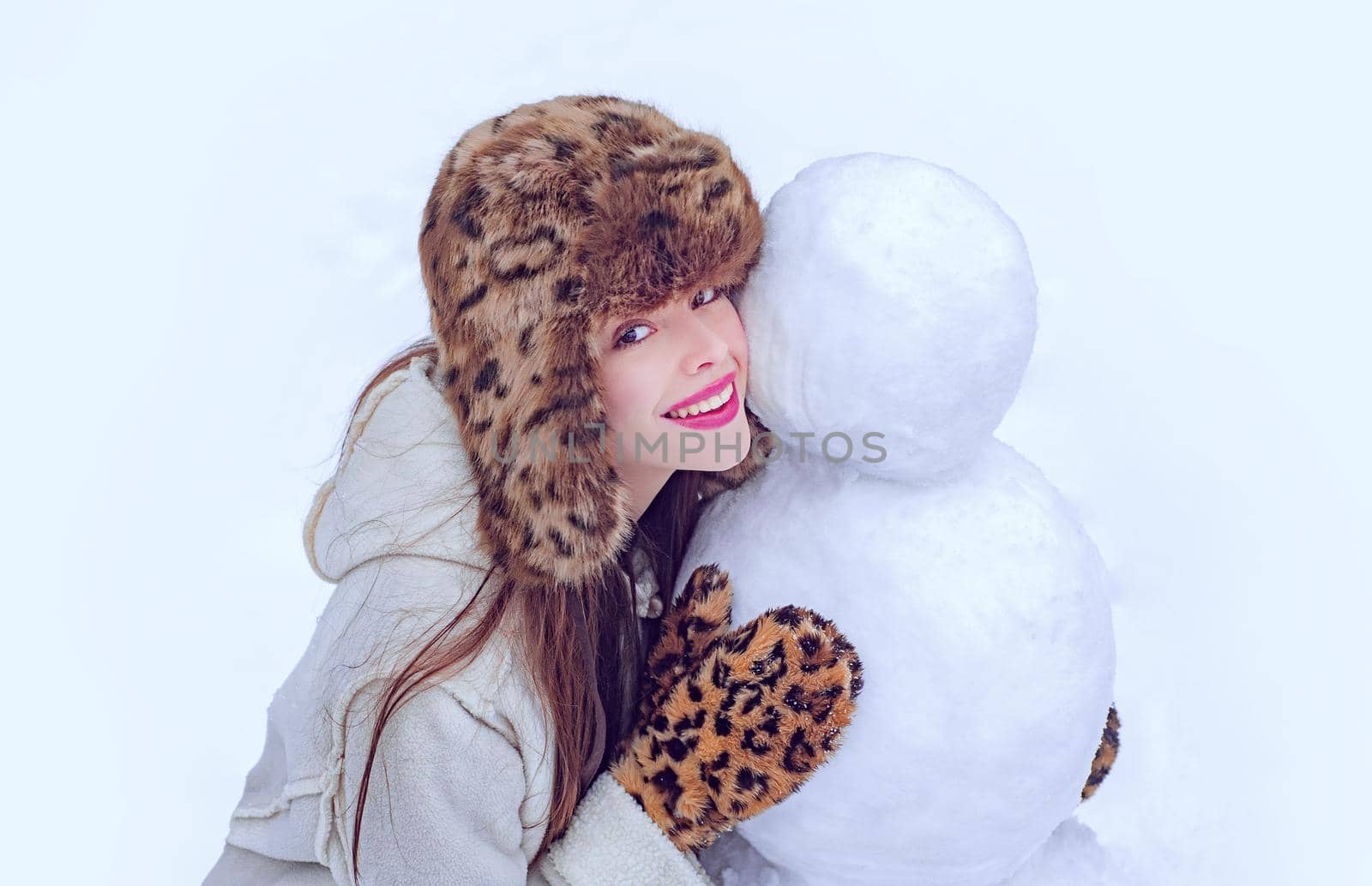 Winter woman. Winter girl making snowman. Happy girl playing with a snowman on a snowy winter walk. Winter emotion. Young woman winter portrait
