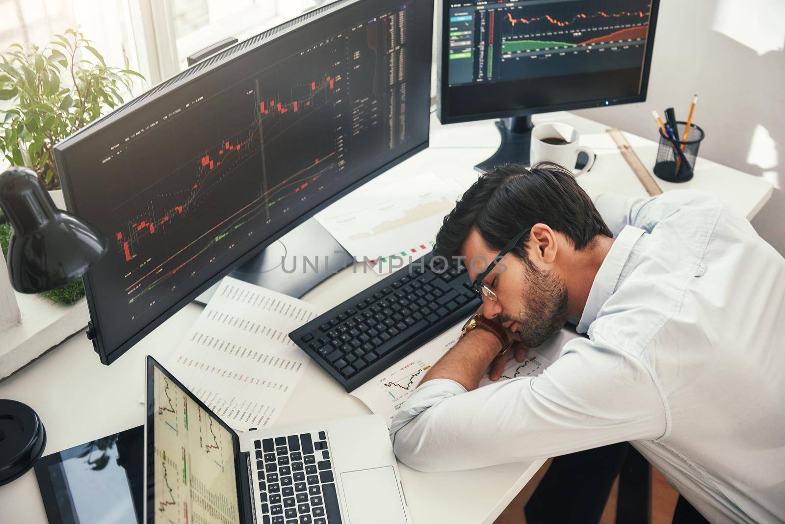 I need to relax. Tired young bearded trader in formal wear sleeping on the desk while working late in his modern office by friendsstock