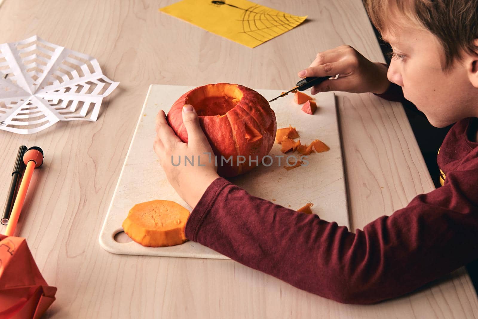 Halloween, decoration and holidays ideas- close up of kid with knife carving pumpkin or jack-o-lantern. 6 years boy has homefamily fun activity. Mom spending time with son together.