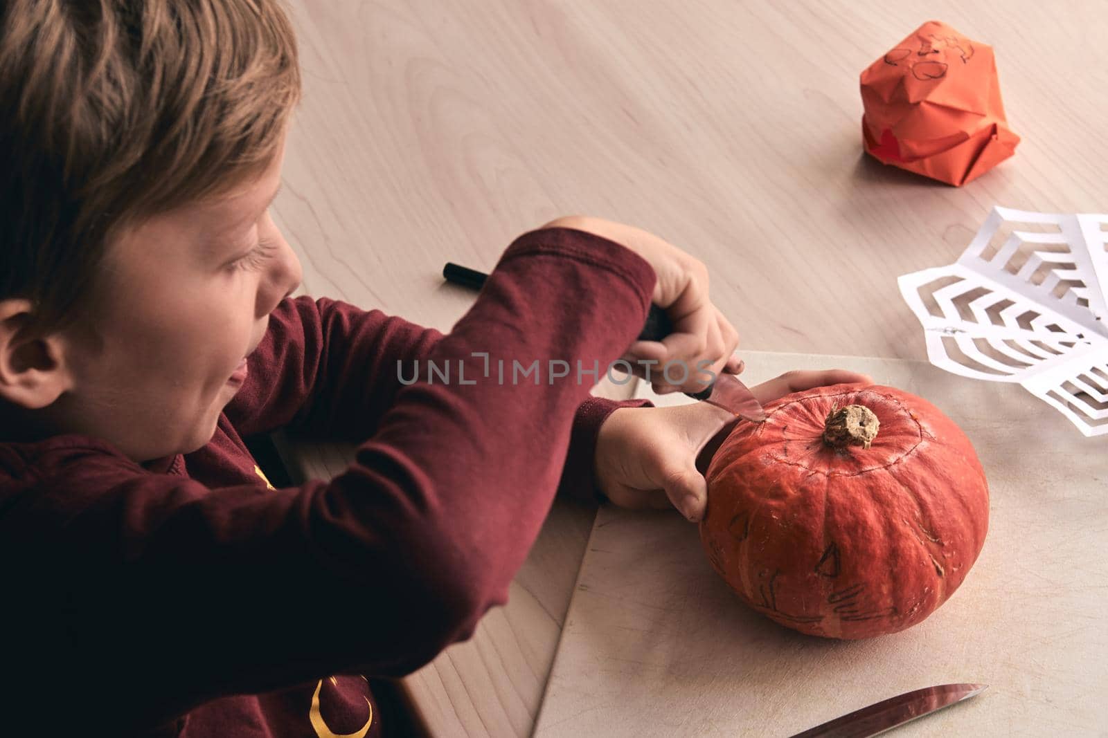 Halloween, decoration and holidays ideas- close up of kid with knife carving pumpkin or jack-o-lantern. 6 years boy has homefamily fun activity. Mom spending time with son together by OneWellStyudio
