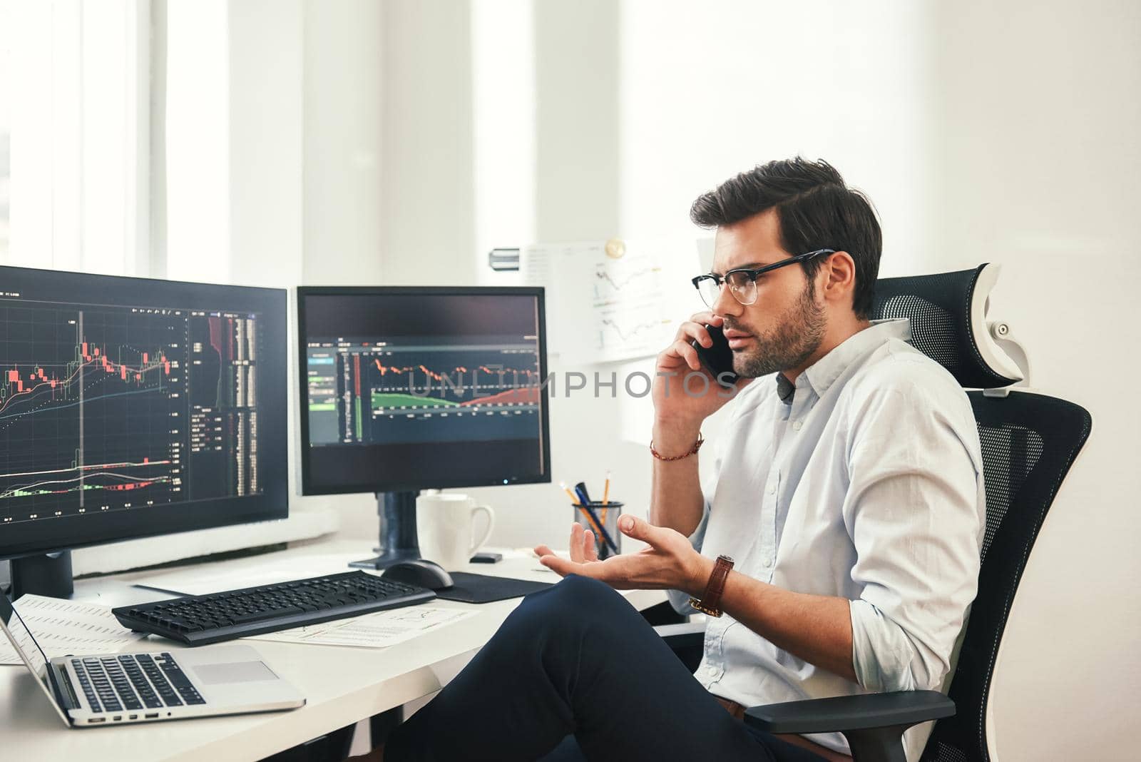 Really Worried bearded businessman or trader in formalwear and eyeglasses is talking with client and gesturing while sitting in modern office. Trade concept. Investment concept. Modern technologies